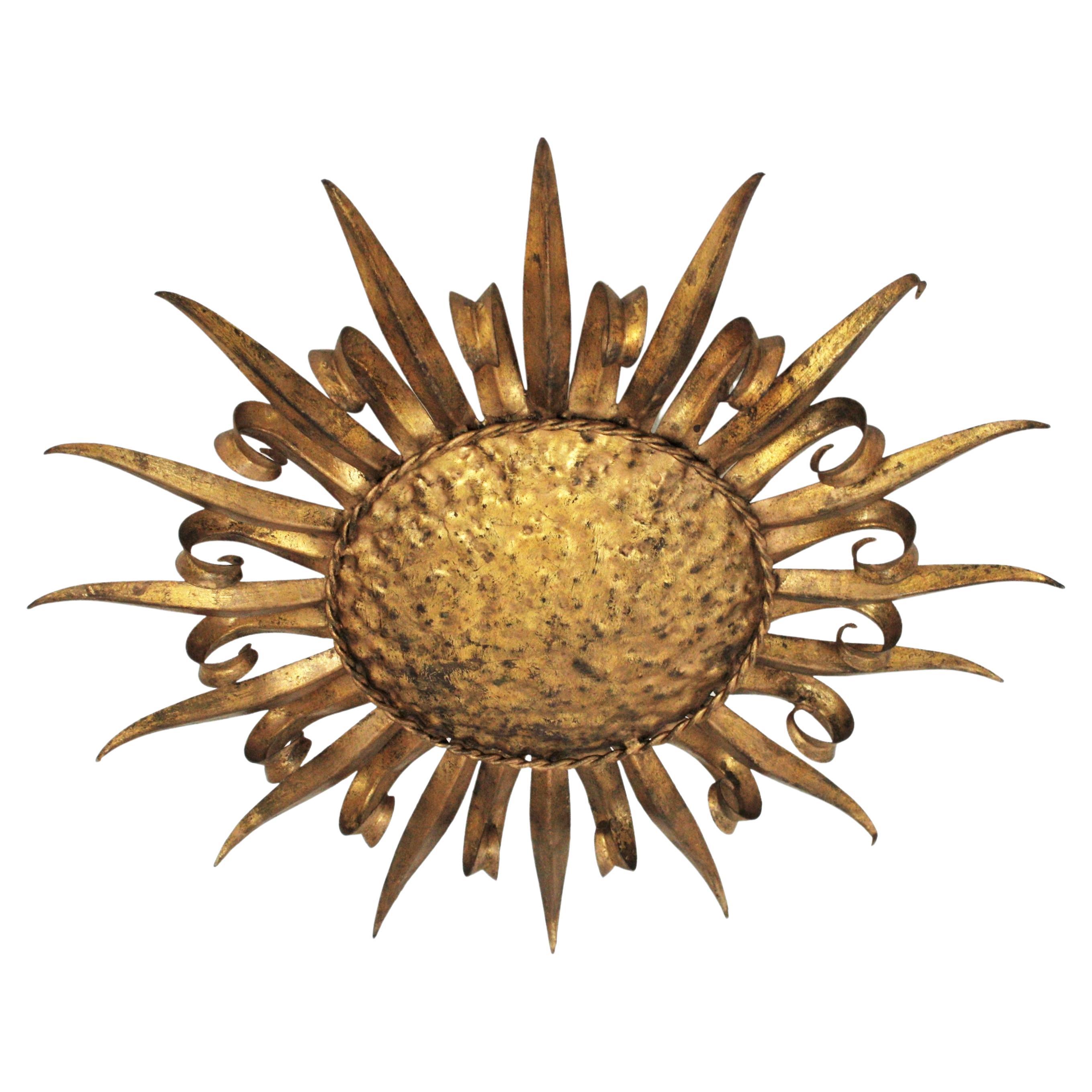 French midcentury gilt iron eyelash sunburst ceiling light fixture / wall sconce, 1950s.
A hand-hammered large gilt iron sunburst light fixture with alternating eyelash ended rays and straight rays. Handcrafted in France at the mid-20th century