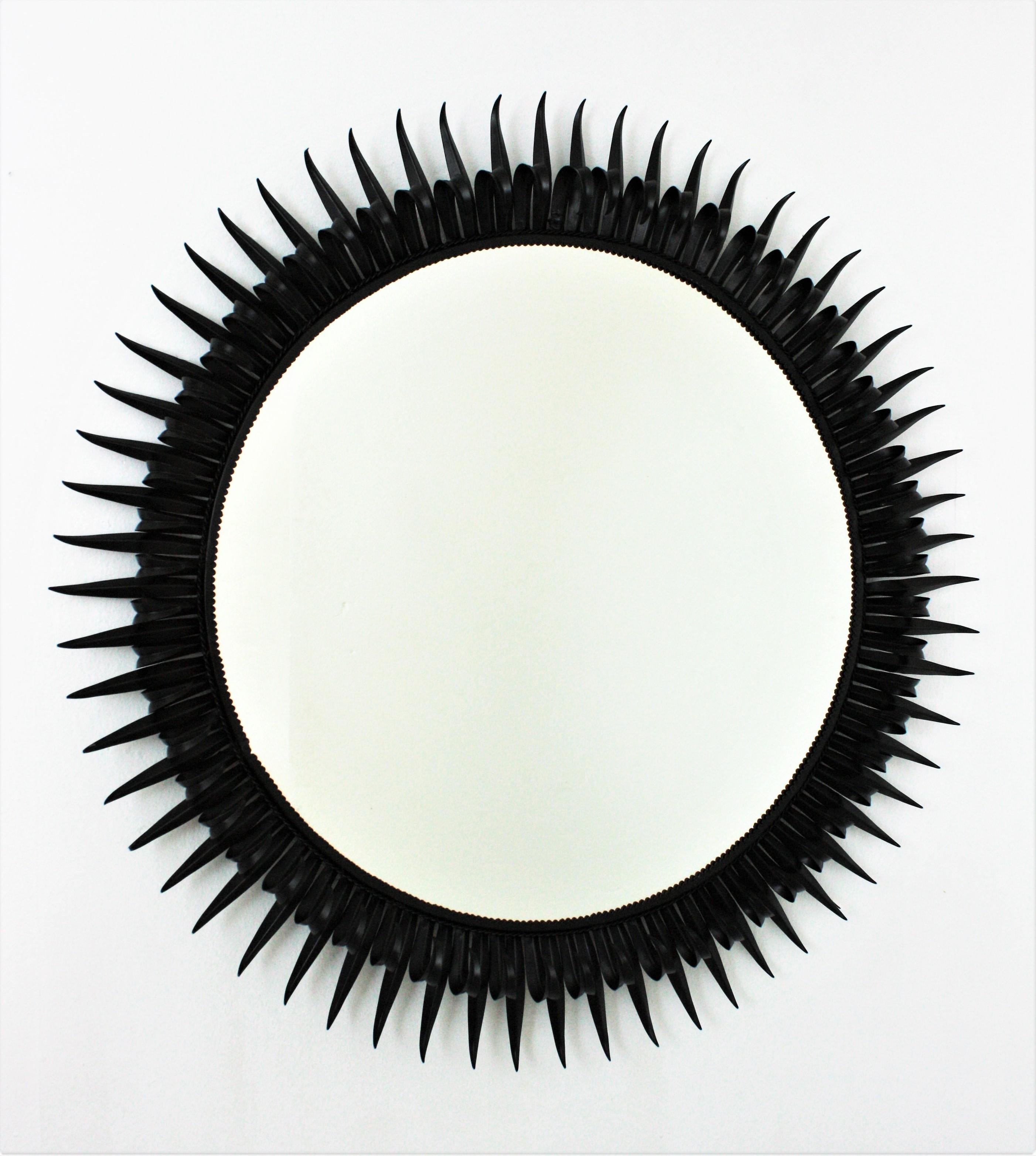 Huge double layered eyelash black iron eyelash sunburst mirror. France, 1950s
The frame is made by alternating hand-hammered curved and straight rays in eyelash shape. The iron is finished in black paint.
This sunburst mirror was manufactured at