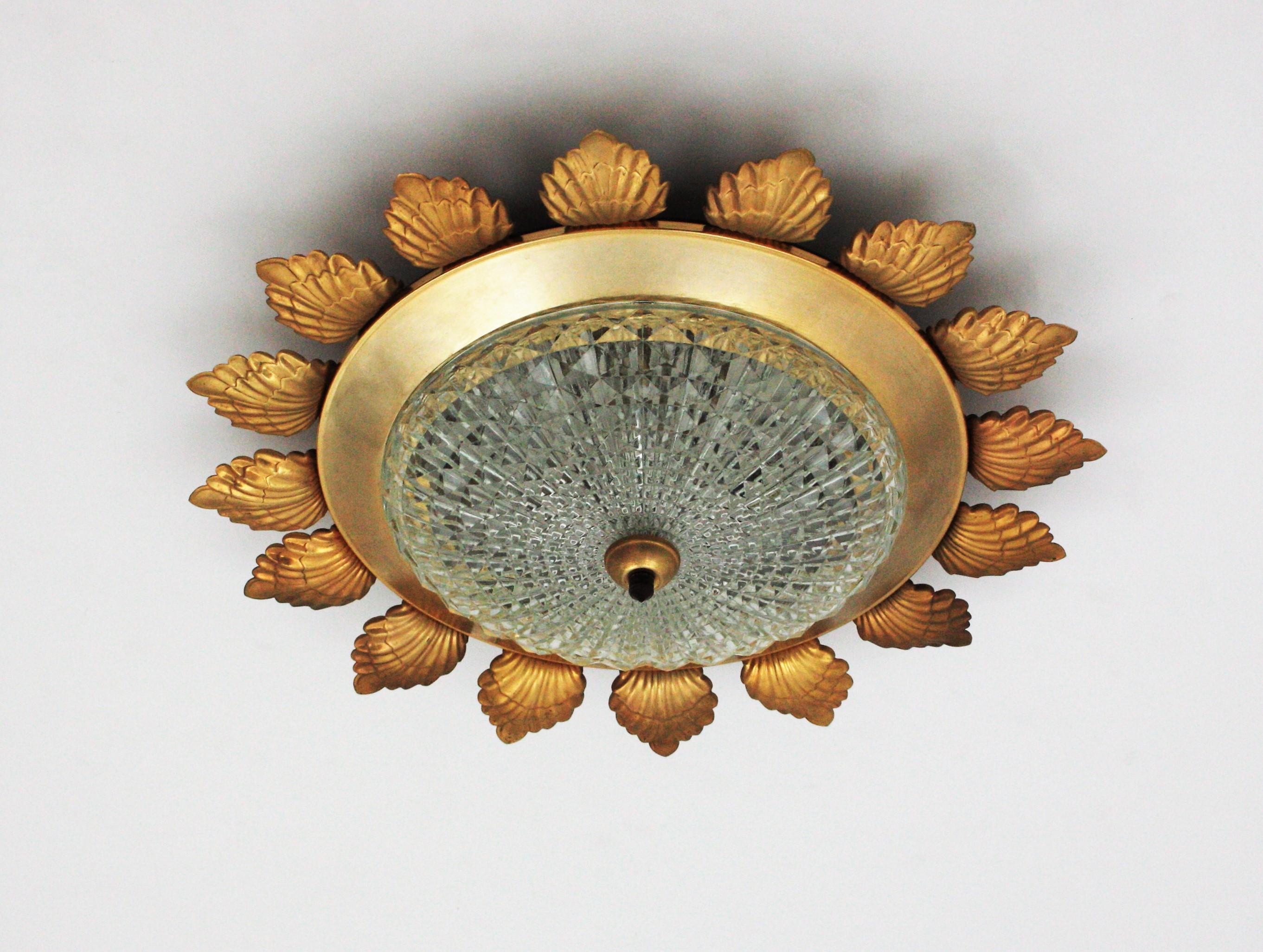 Flower shaped flush mount, Gilt Metal, Pressed Glass, Spain, 1960s.
This large ceiling lamp features a gilt metal flower shaped frame surrounding a central pressed glass shade. 
It has a beautiful design combining neoclassical style and Midcentury