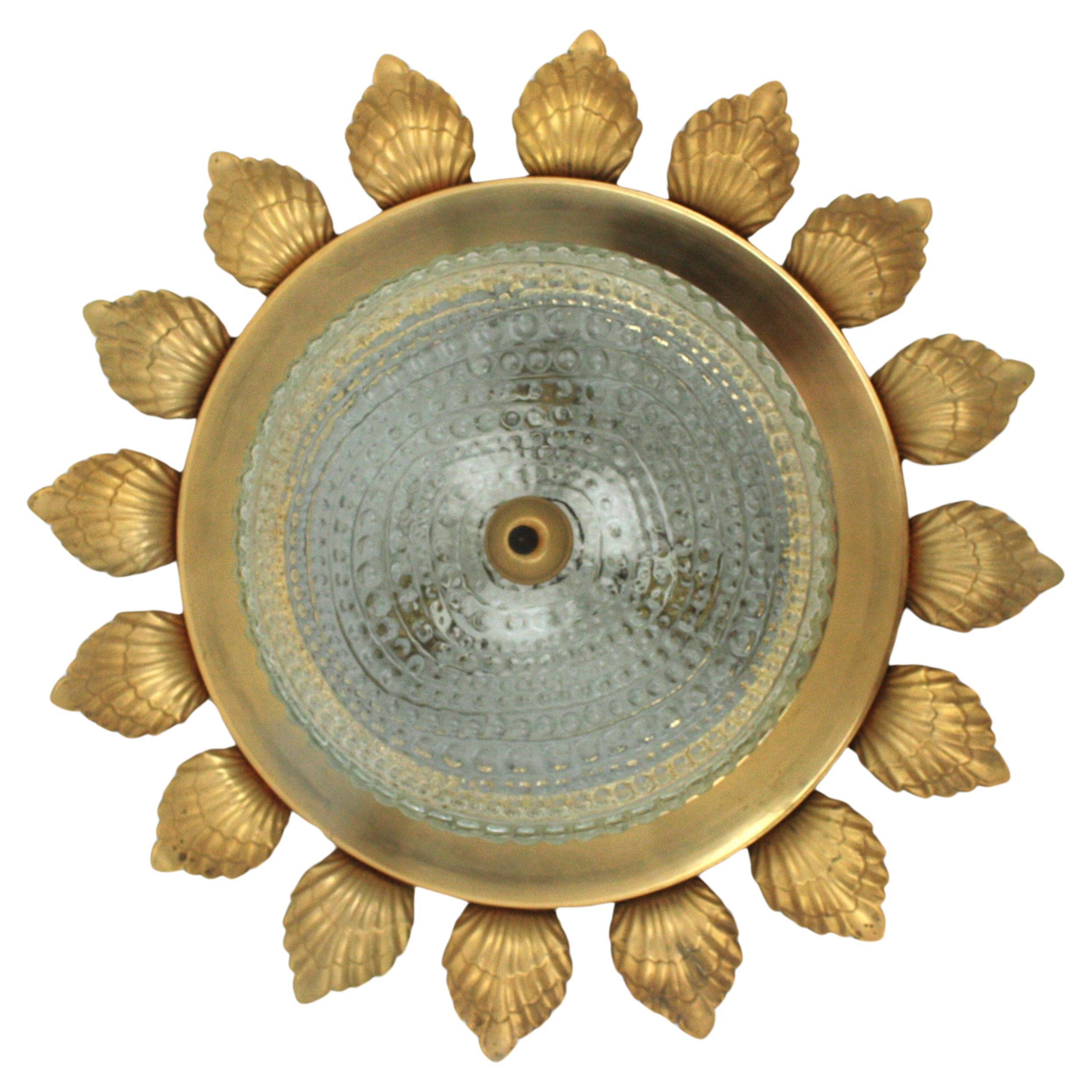 Flower shaped flush mount, Gilt Metal, Pressed Glass, Spain, 1960s.
This large ceiling lamp features a gilt metal flower shaped frame surrounding a central pressed glass shade with bubble pattern thorough.
It has a beautiful design combining