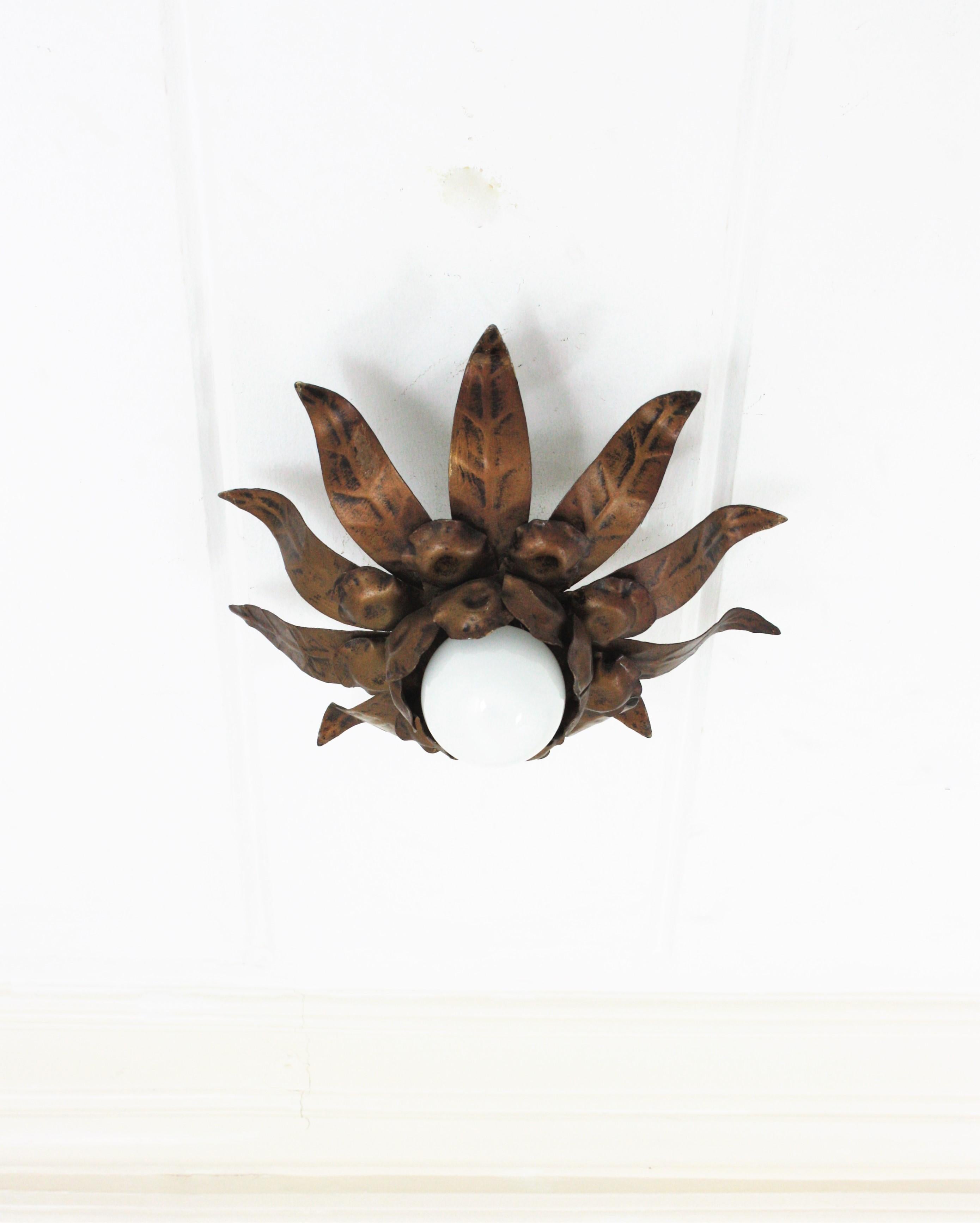 Flower Sunburst Flush Mount, Gilt Iron. Spain, 1960s.
This ceiling light features a flower shaped frame with three layers of leaves in different sizes surrounding a central exposed bulb. Patinated in bronze gilt color.
This sunburst light fixture