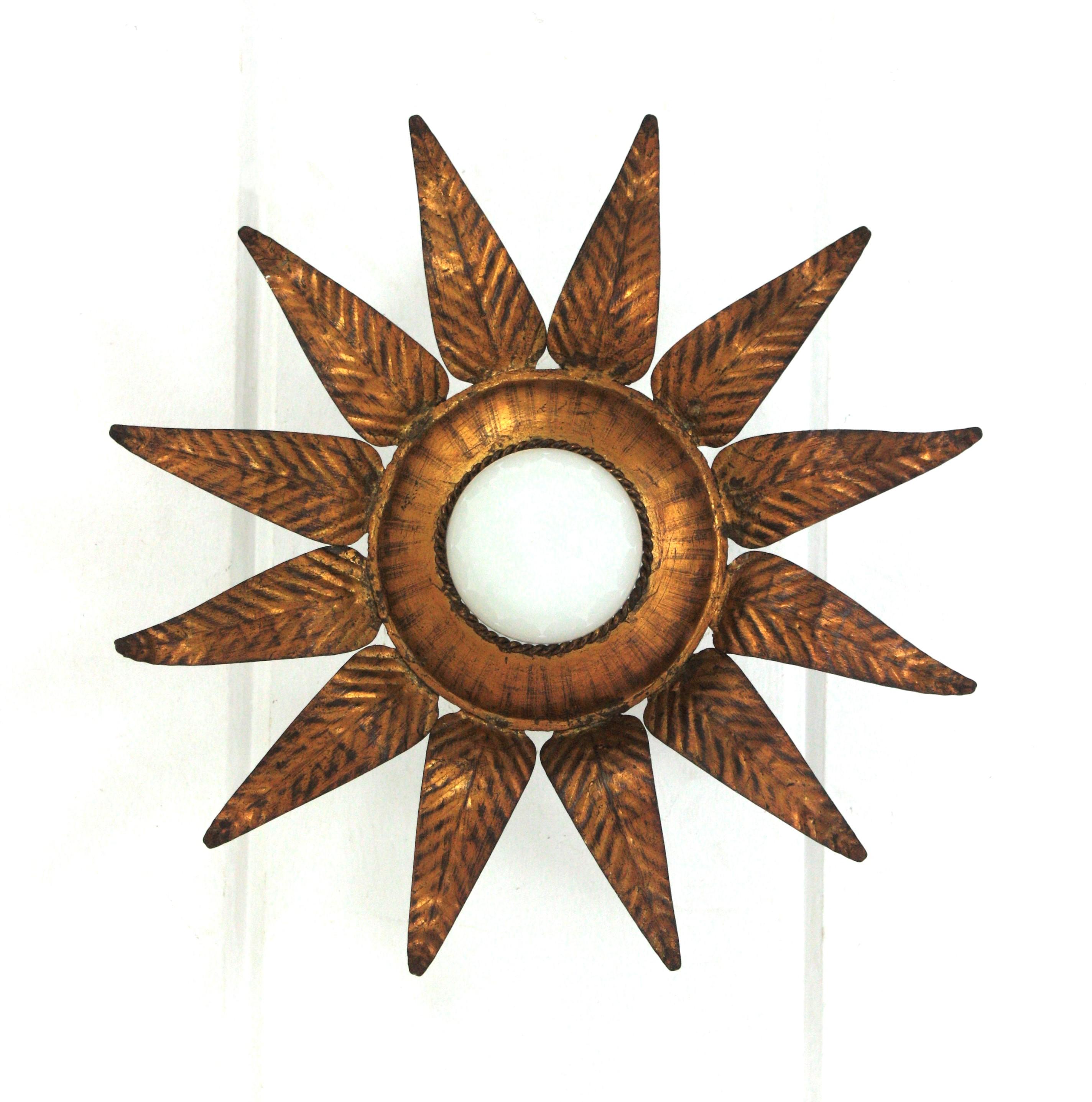 Flower Leafed Sunburst Flush Mount, Gilt Iron, Gold Leaf,  Spain, 1950s.
This ceiling light features a flower shaped frame with a layer of  leaves in surrounding a central exposed bulb. Each leaf has a detailed pressed work.
Original gilding in gold