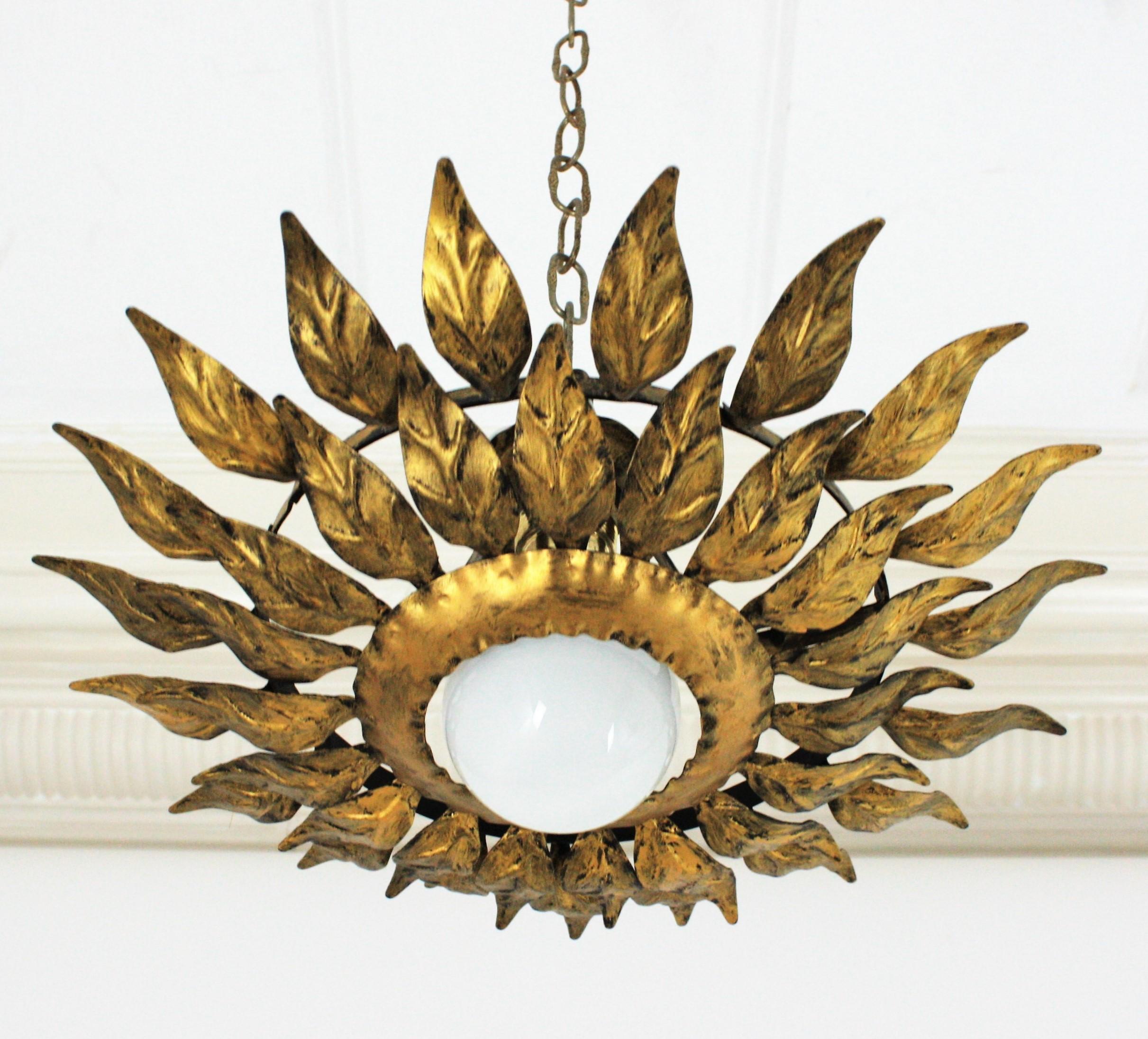 Gilt metal double layered leafed sunburst ceiling flush mount. Spain, 1960s.
An eye-catching sunburst or flower burst ceiling flush mount with two layers of gilded leaves surrounding a central exposed bulb.
It can be placed flush mounted or as a