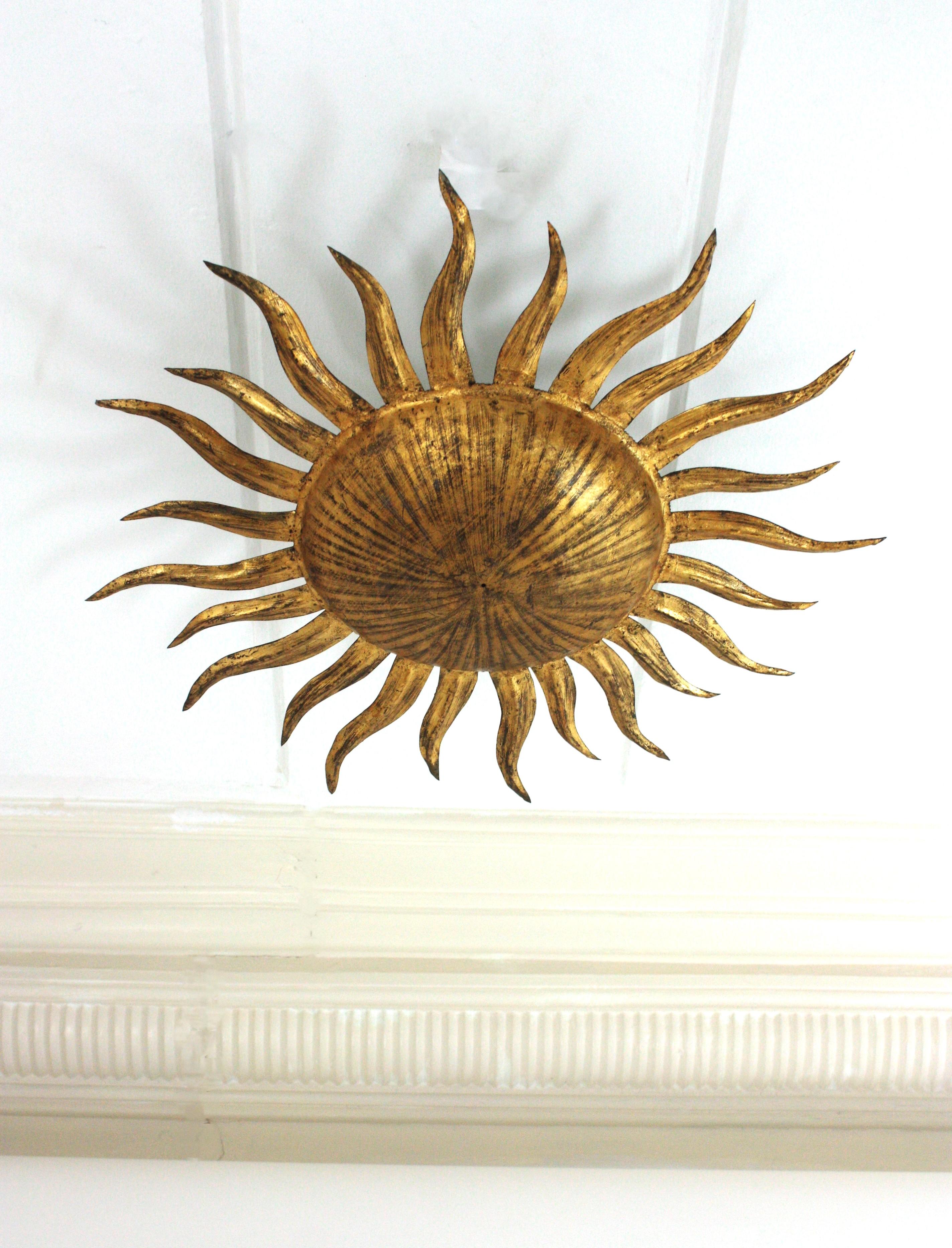 Eye-catching gilt wrought iron sunburst ceiling flush mount in the style of Brutalism. Manufactured by Ferro Art, Spain, 1940s-1950s.
Nicely adorned by striped marks on the gilded surface. It has a terrific aged patina showing its original gold leaf