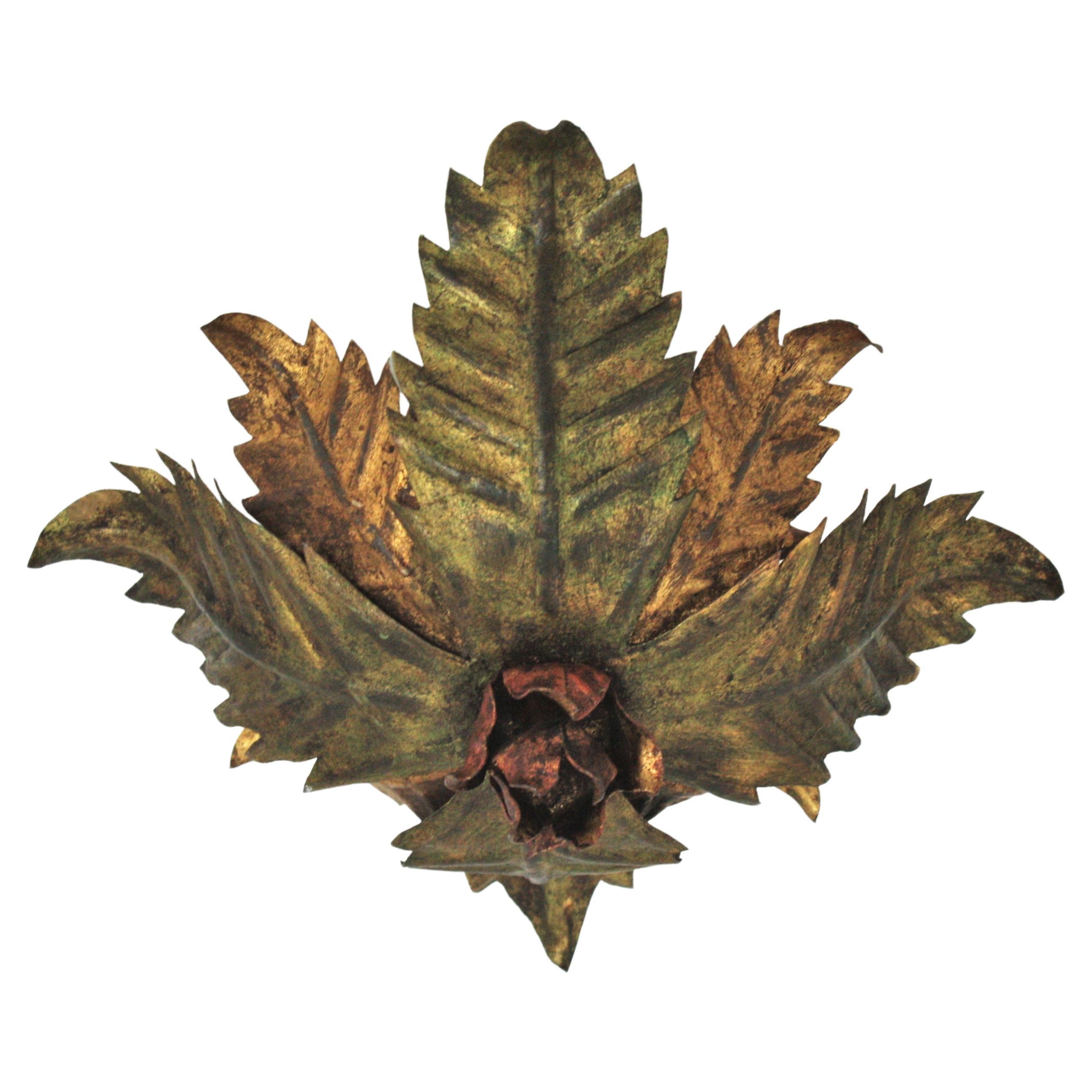 Lovely hand-hammered gilt iron floral ceiling light fixture with leaves and a central rose accent. Spain, 1950s.
The leaves are gilded in two-tone: golden and green color. It has a decoration with an small rose with red accents at the central