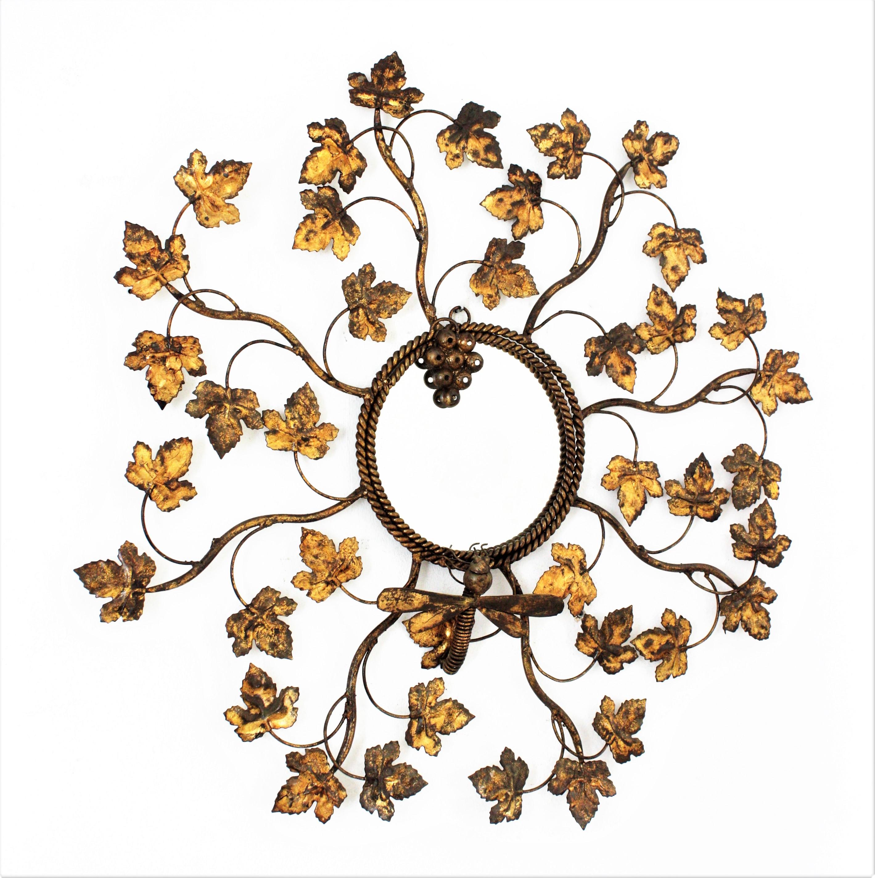 Naturalistic Design sunburst mirror, Gilt Metal, Gold Leaf, France, 1950s.
One of a kind sunburst mirror featuring a frame comprised by branches with vine leafs adorned with a bunch of grapes and a dragon fly.
This mirror was handcrafted at the