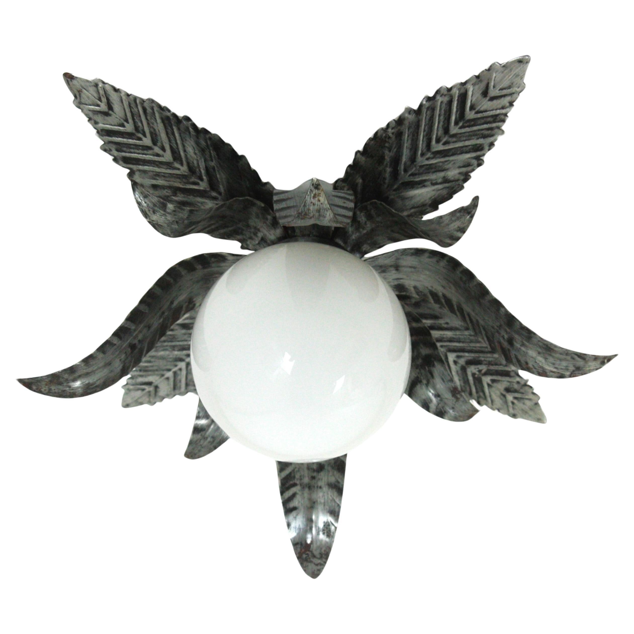 Leafed Flush Mount or Wall Sconce in Silvered Iron with Glass Globe
Midcentury flower or sunburst ceiling lamp, silver gilt metal, milk glass. Spain, 1950s-1960s.
This flush mount features a flower burst or sunburst with double layer of leaves