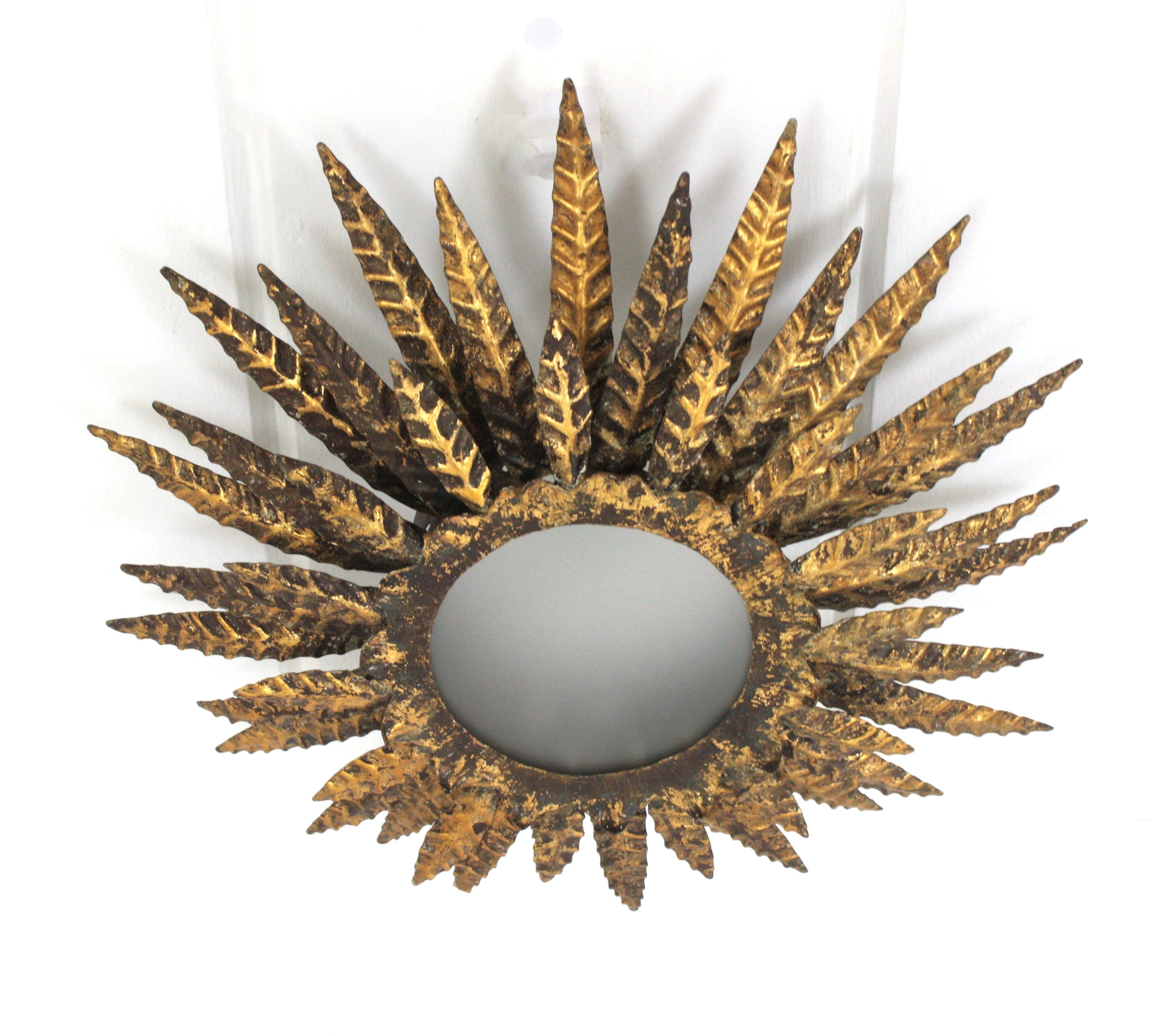 Wunderschöne Brutalist vergoldetes Eisen und Glas sunburst flush mount Deckenleuchte oder Kronleuchter. Frankreich, 1950er Jahre.
Diese Sunburst-Leuchte zeichnet sich durch eine dreifache Schicht von Blättern / Strahlen aus, die eine zentrale