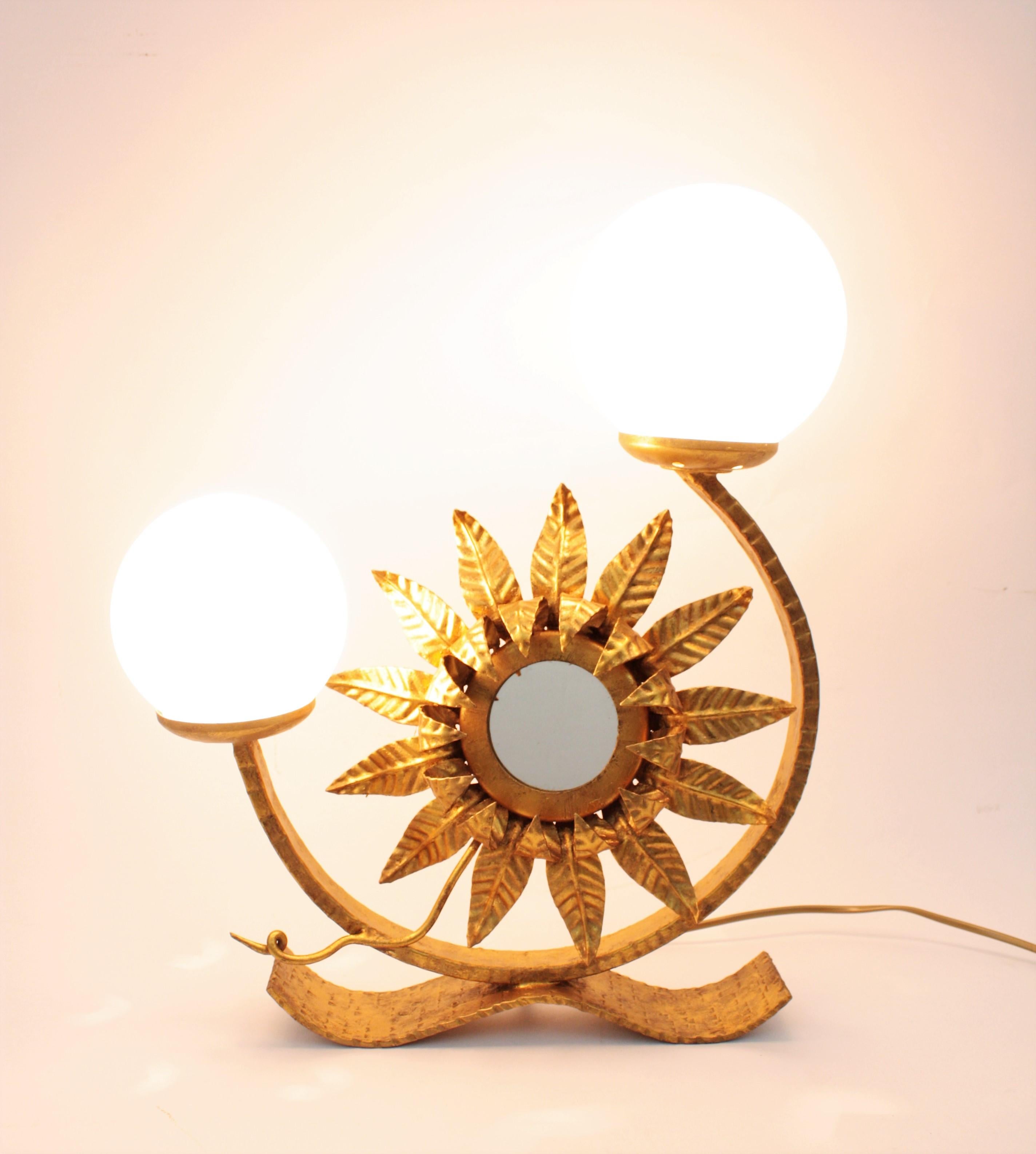 Wrought iron Spanish two-light table lamp with opaline glass globe shades and decorative sunburst mirror.
This eye-catching table lamp with a sunflower or sunburst mirror between the lights.
Outstanding naturalistic design with Hollywood Regency