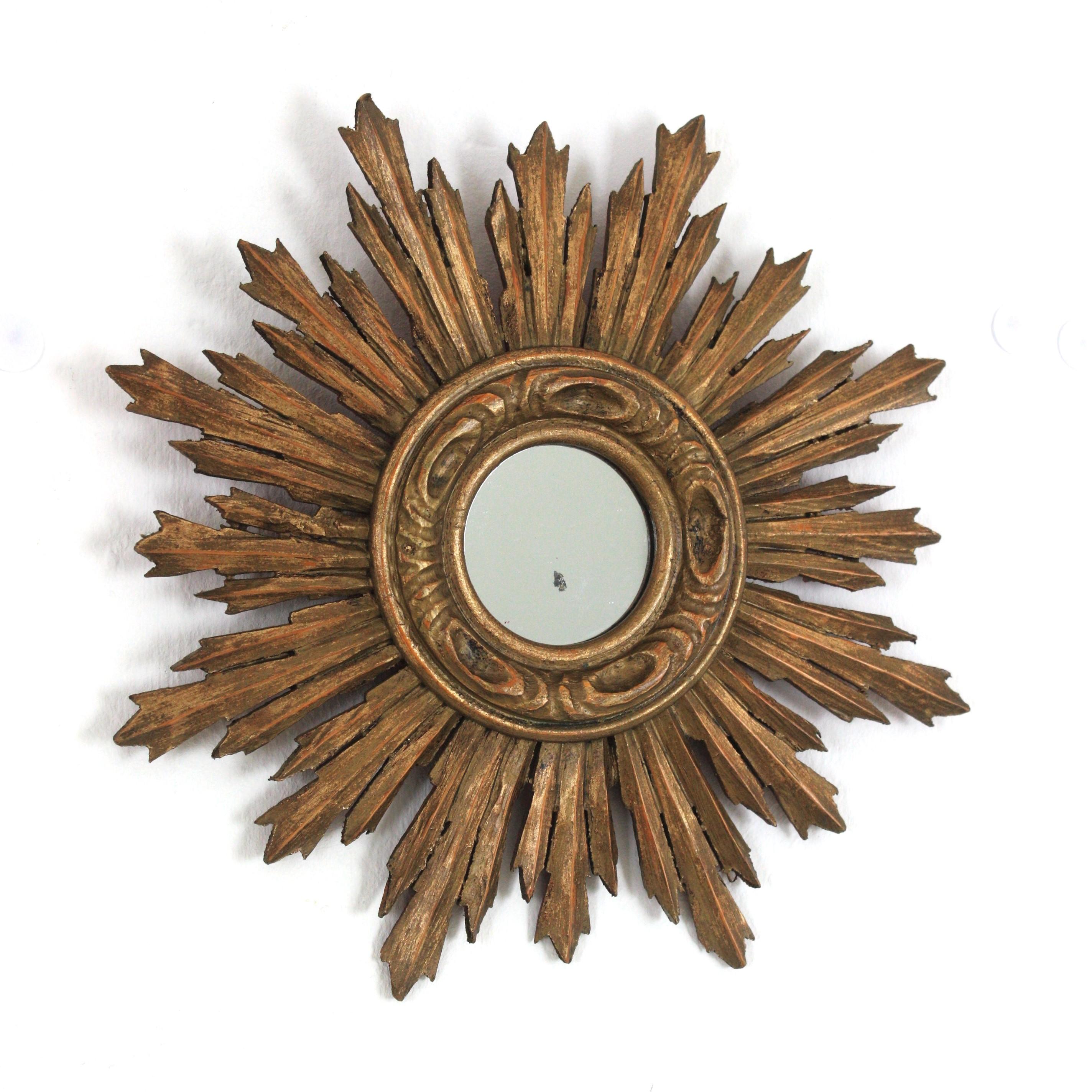 Miroir en bois doré de style baroque espagnol, 1940s-1950s
Joli miroir en bois doré de style baroque de taille réduite avec finition à la feuille d'or. 
Ce magnifique miroir miniature en forme de soleil a un cadre composé de rayons de différentes