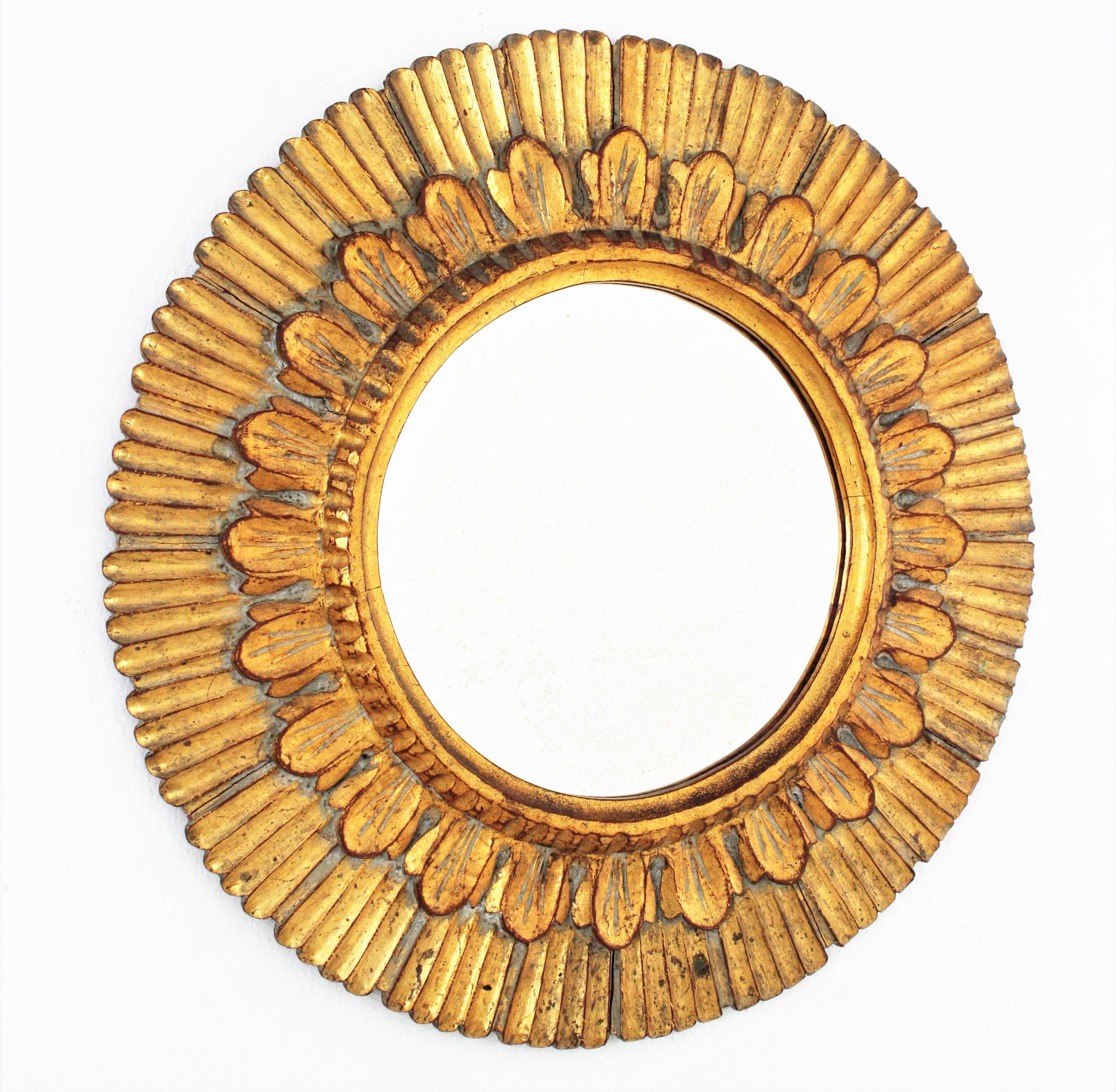Sunburst mirror, carved wood, gold leaf, Spain, 1950s.
Carved wood and gold leaf gilding. Eye-catching design combining Baroque, Midcentury and Hollywood Regency accents. The frame has striped carving details and gold leaf finish.
 It has a nice