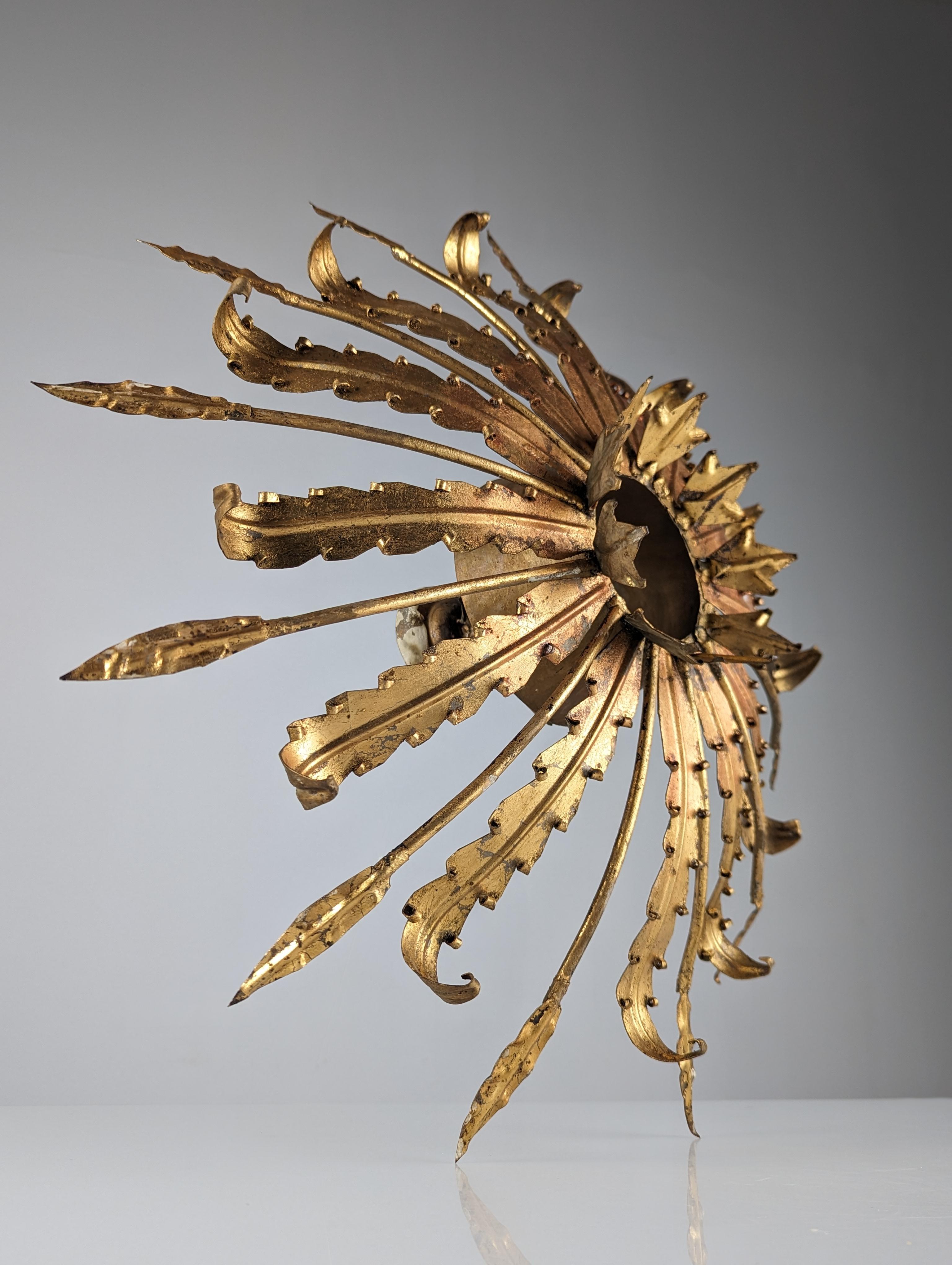 Monumental sun ceiling lamp from the 1950s made of gold metal, its rays in the shape of wide leaves and elegant thin interspersed leaves create a beautiful combination. It has three light points, one of them central designed to place a globe or