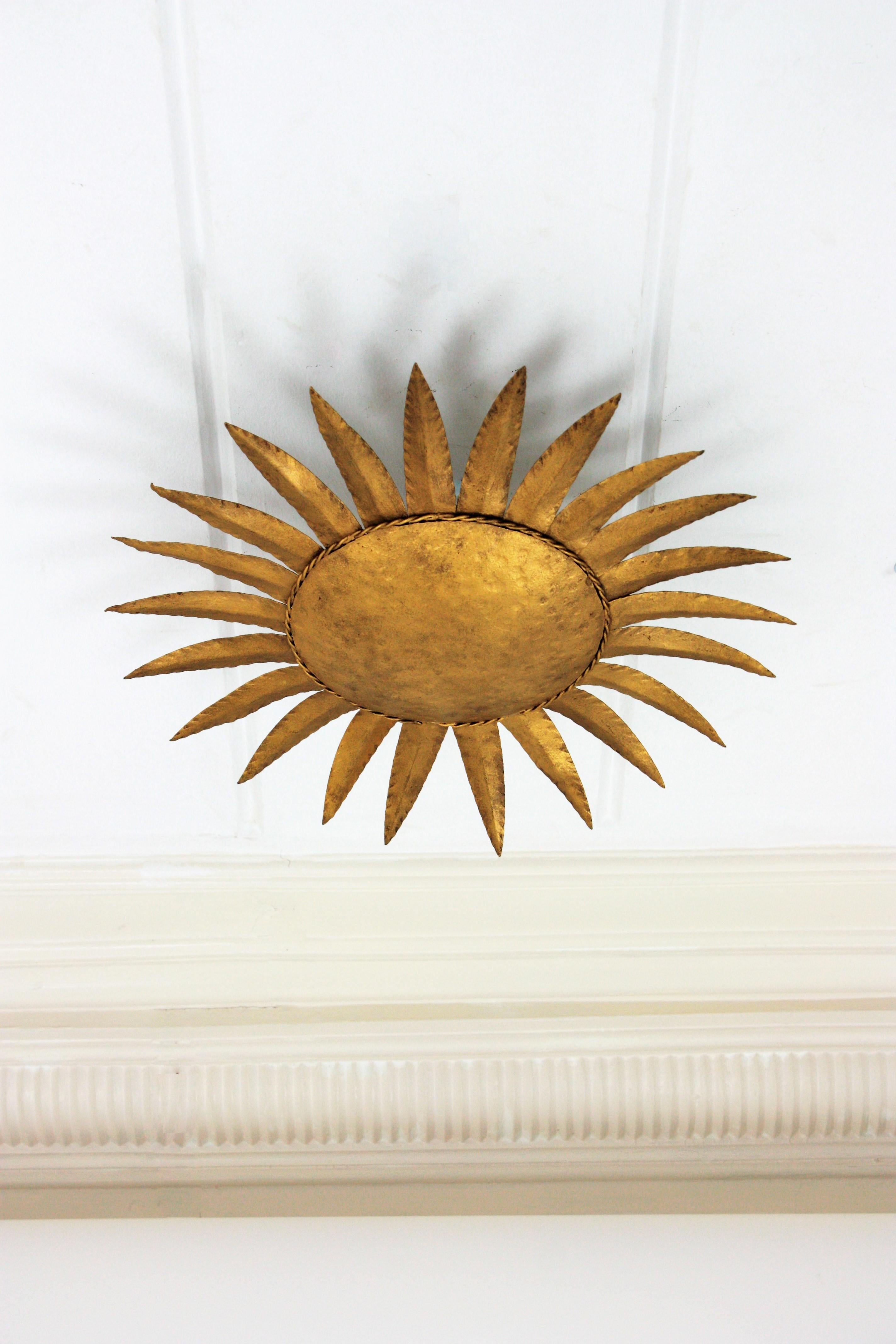 Eye-catching gilt wrought iron sunburst ceiling flush mount in the style of Brutalism. Manufactured by Ferro Art, Spain, 1960s.
This hand-hammered iron gilded sunburst flush mount or wall sconce will be a nice midcentury Brutalist accent wherever