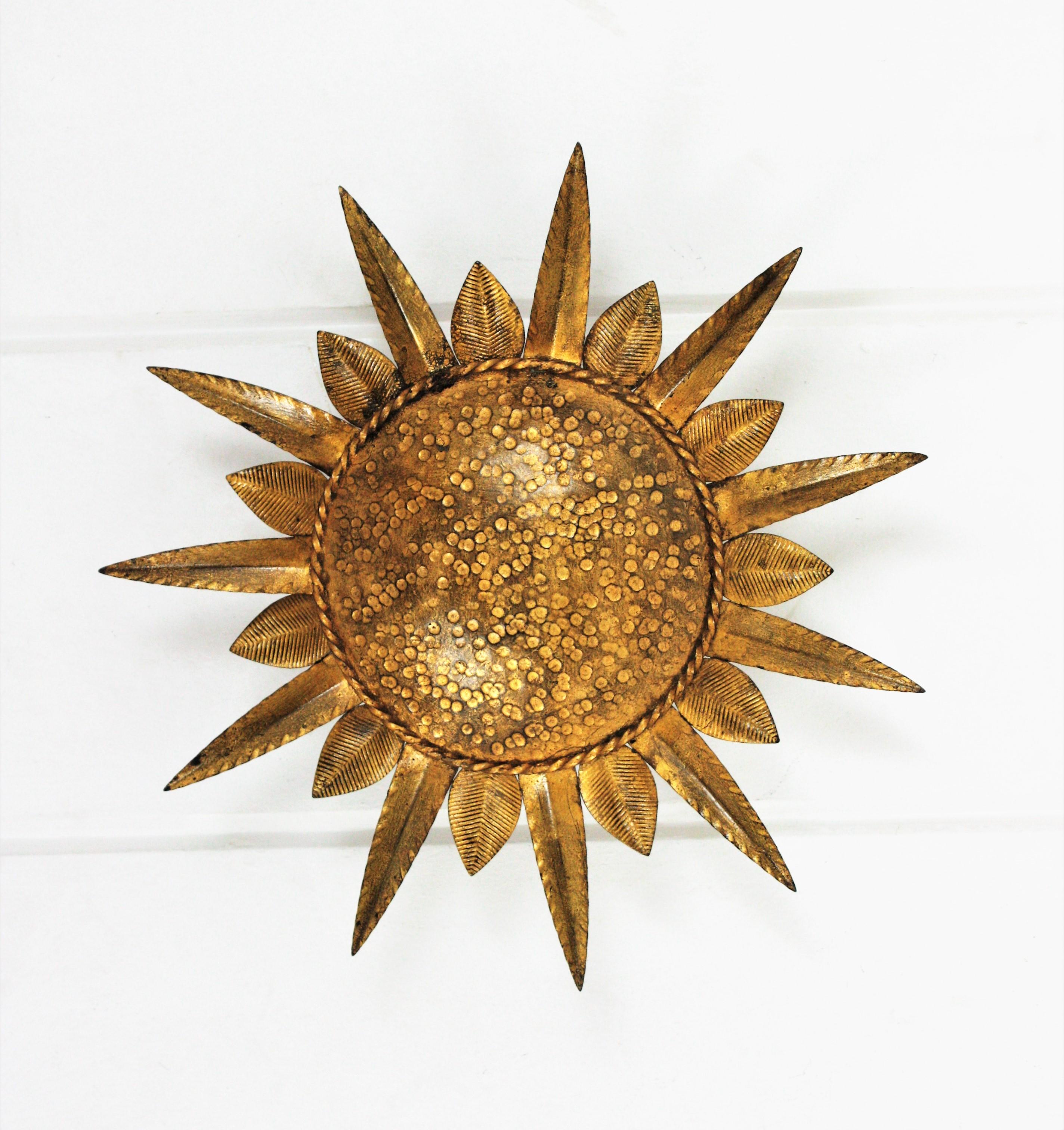 Lovely gold leaf gilt iron leafed sunburst flush mount. Manufactured by Ferro-Art. Spain, 1950s-1960s.
This ceiling flushmount features an iron structure with a central round panel framed by alternating short and long leaves
The central part is