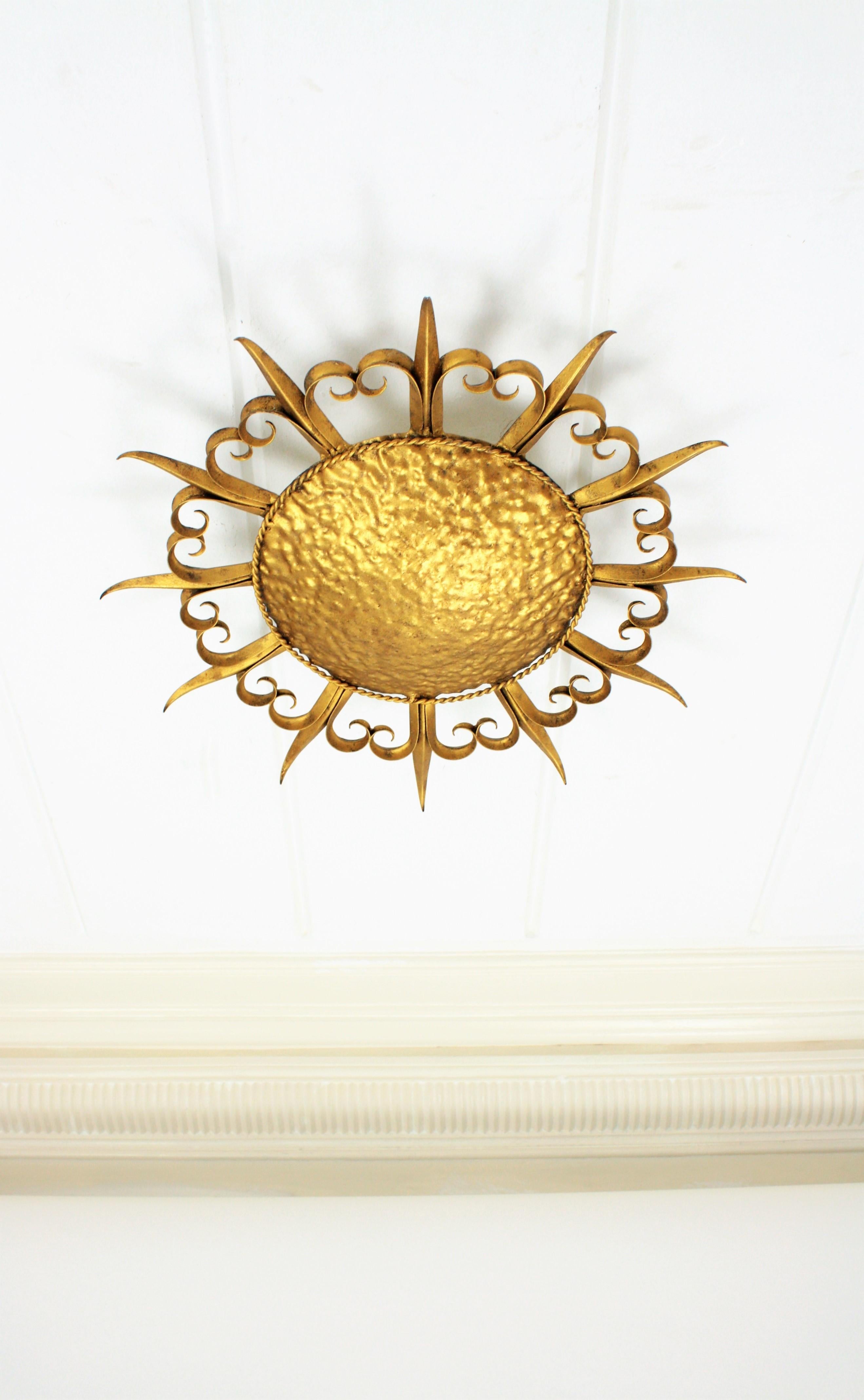 French midcentury gilt iron eyelash sunburst ceiling light fixture / wall sconce, 1950s.
A hand-hammered large gilt iron sunburst light fixture with alternating eyelashed rays and straight rays. Handcrafted in France at the mid-20th century period.
