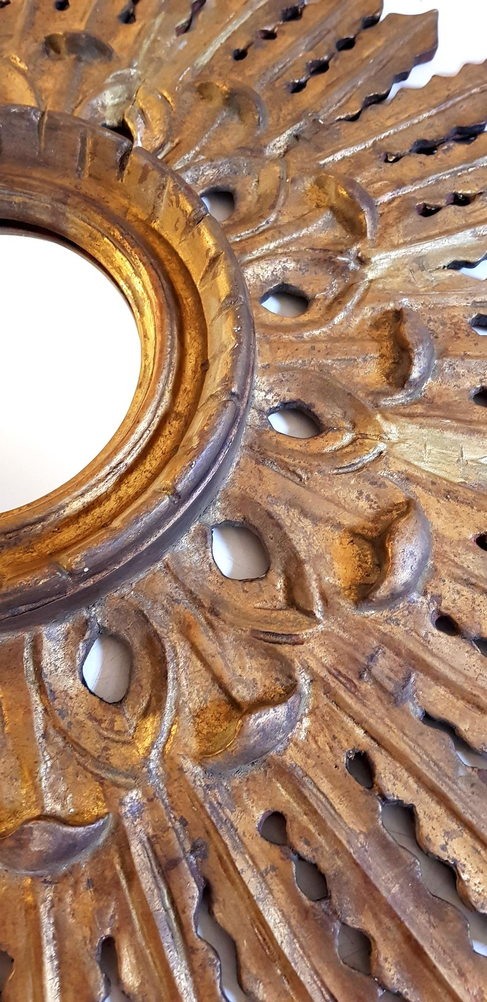 A Spanish 1950s wood carved sunburst mirror finished with gesso and gold leaf and a central frame surrounding the glass. Measure: Diameter of the mirror is 13 cm.