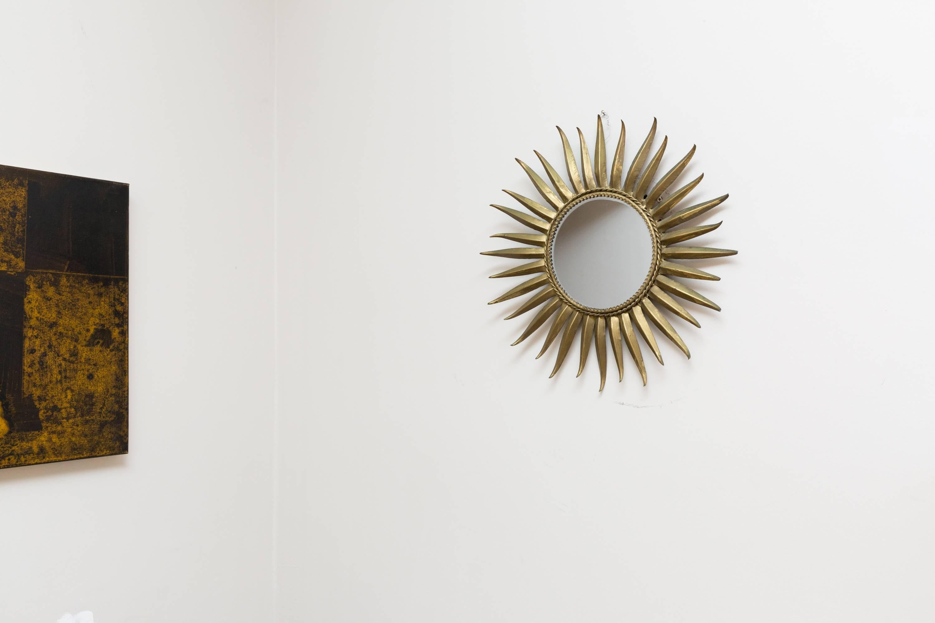 Elegant sunburst mirror, France, circa 1950, brass frame, edged in with a brass cord, old shaped mirror. Measures: Diameter 50, mirror diameter 20 cm. Very nice patination, very good original vintage condition. No chips or scratches in the