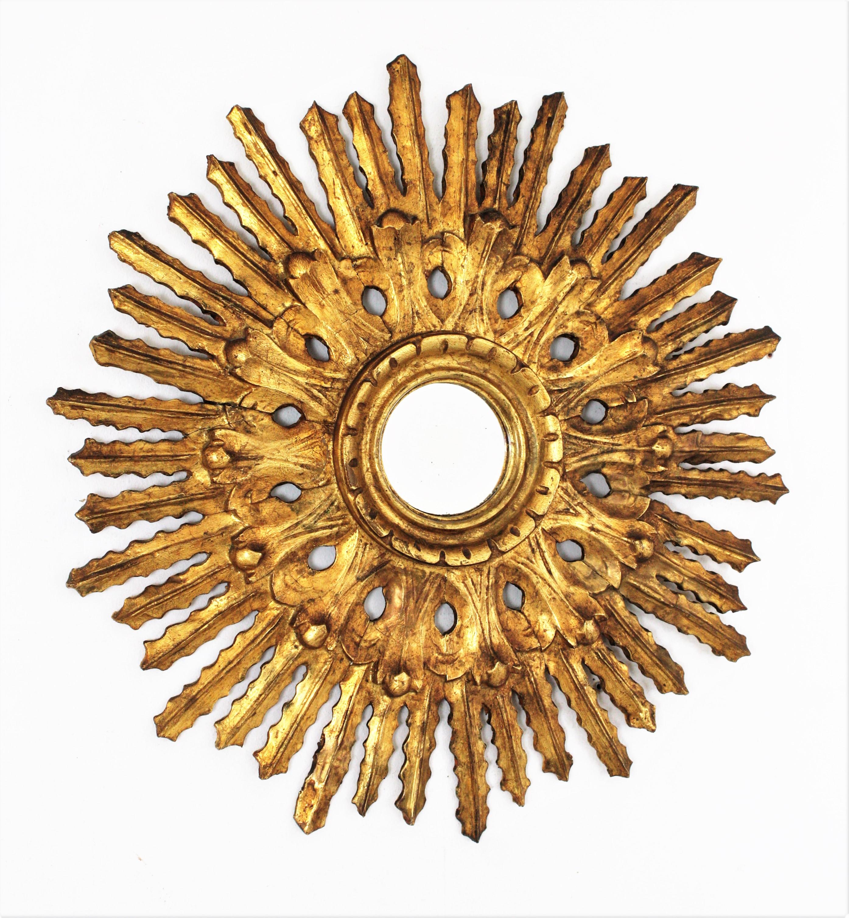 An exquisite finely carved Baroque style sunburst mirror with a carved filigrana decoration surrounding the convex glass. Spain, 1920-1930s.
The sunburst shape and the lovely floral corolla surrounding the glass make this piece highly decorative.