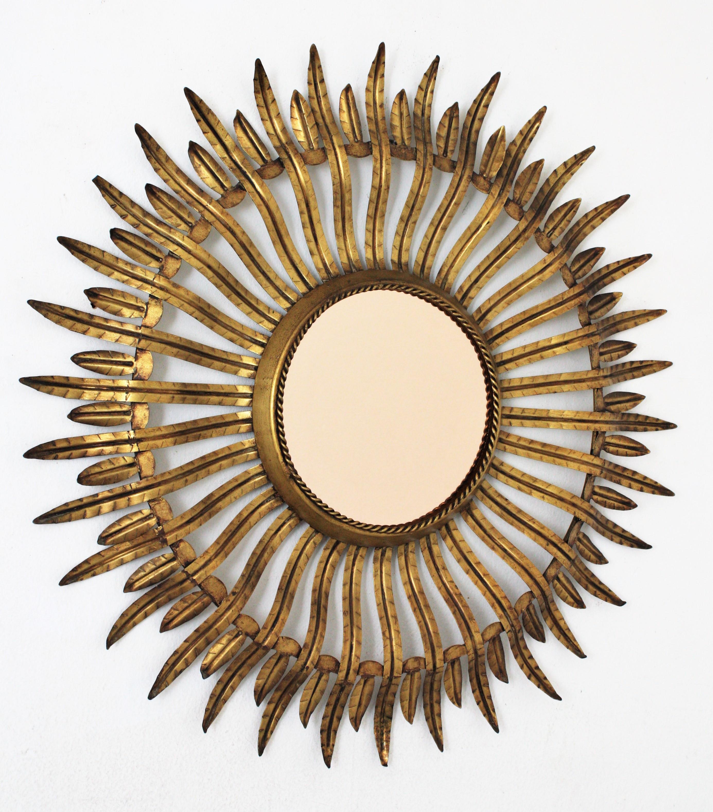 Round Sunburst mirror in Gilt Metal and Smoked Bronze Glass, Spain, 1960s
Beautiful gilt iron double layered sunburst mirror with smoked glass in bronze color.
This sunburst mirror features two layers of alternating long and short leaves