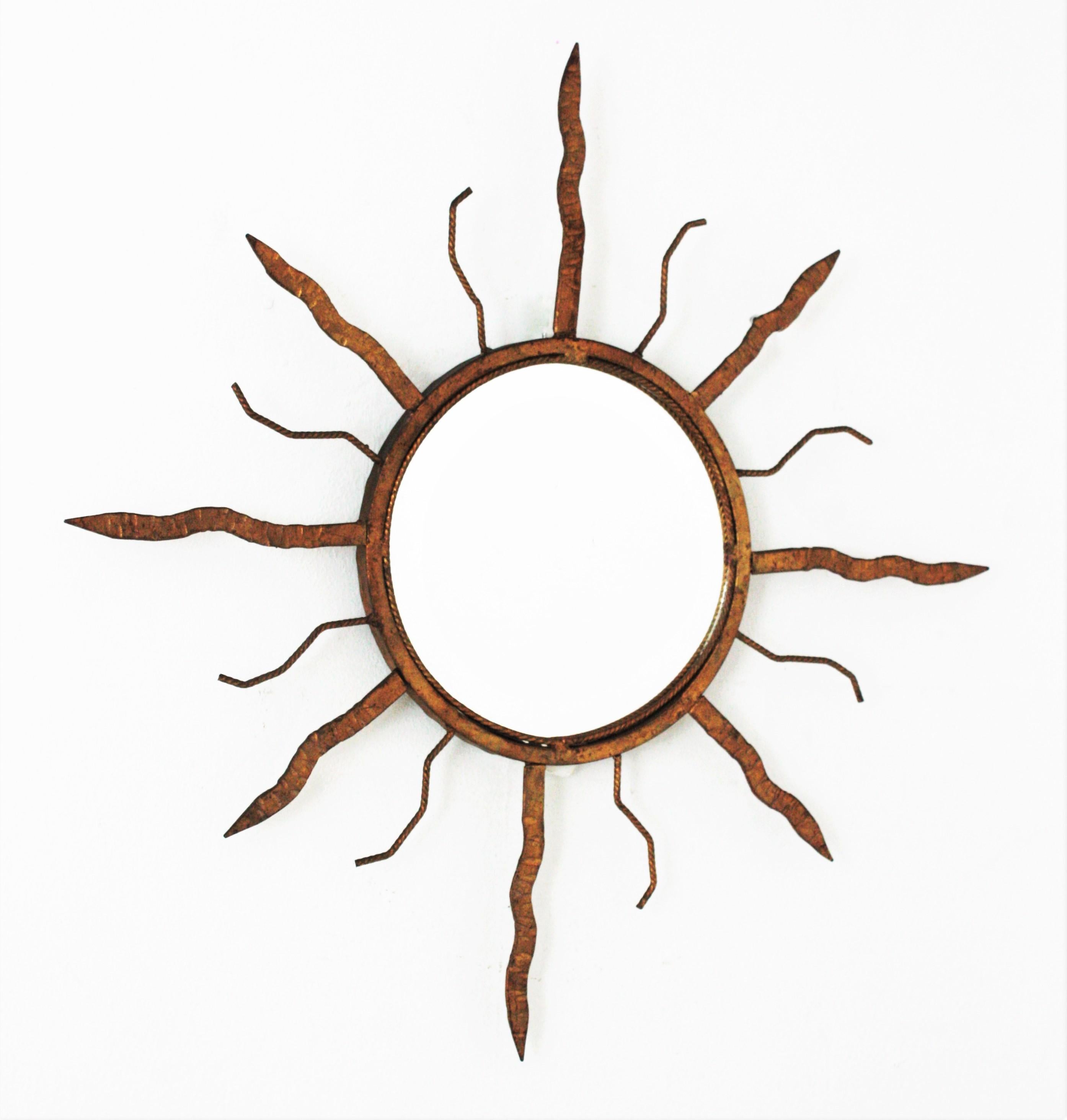 Hand forged iron sunburst mirror with gold leaf finish in the manner of Gilbert Poillerat, France, 1940s-1950s
This eye-catching wrought iron sunburst mirror manufactured at the mid-20th century period. Its design is clearly inspired by those