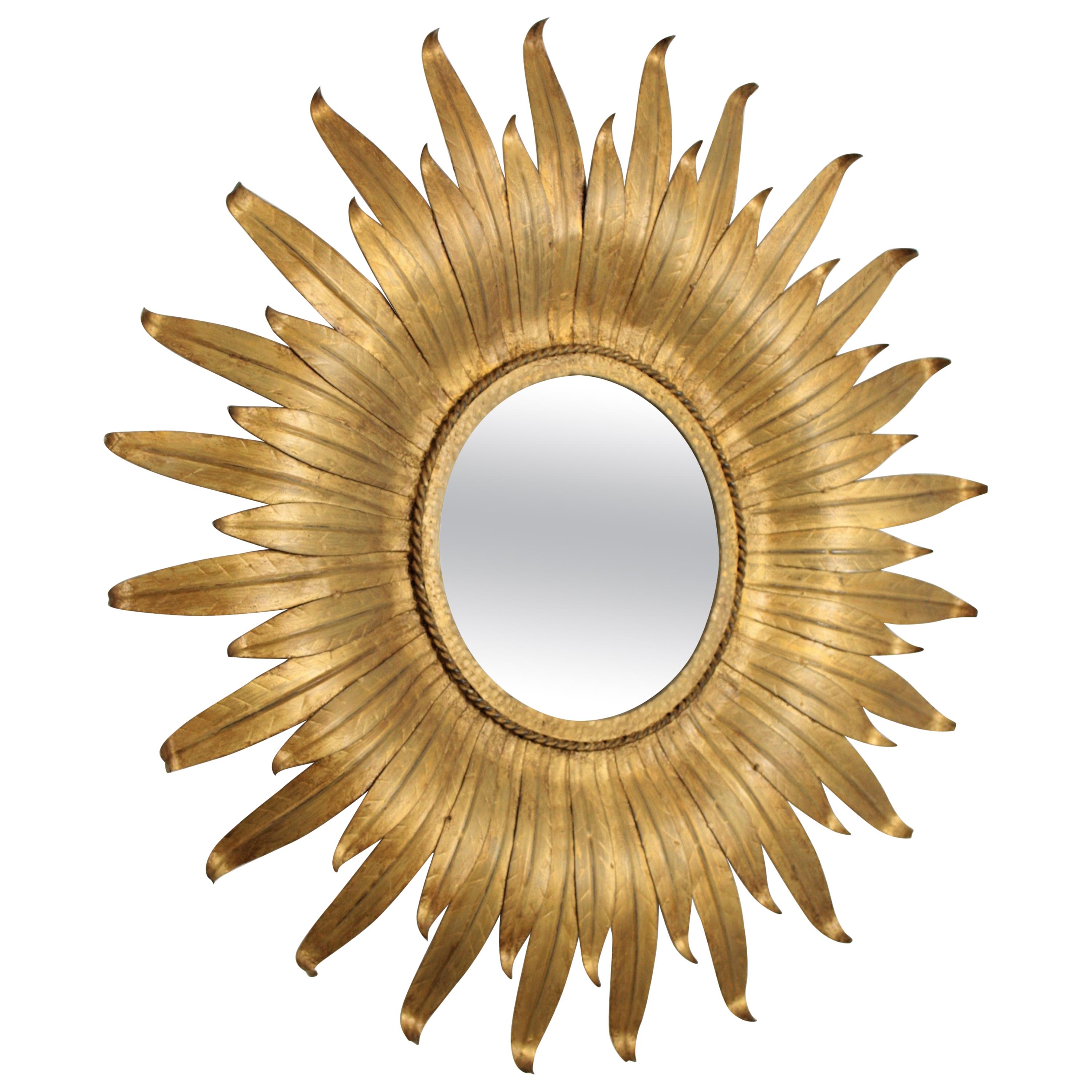 A lovely sunburst flower shaped mirror gilt metal sunburst mirror, Spain, 1950-1960.
This wall sunburst mirror features a circular glass framed with curved gilt leaves in two sizes.
Beautifully handcrafted. It has a nice aged patina.
This mirror