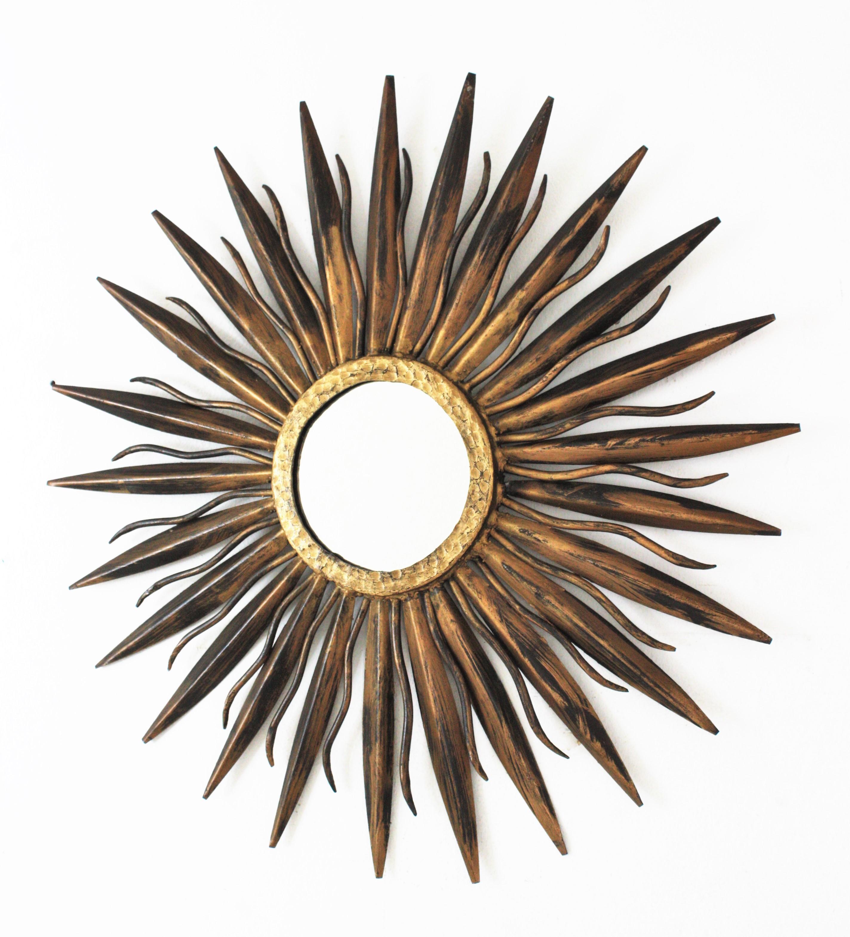 Sunburst mirror in hand forged iron and gilt patina. Spain, 1940s-1950s.
This sunburst mirror features a frame made of hand forged spikes and leaves attached to a central ring. Gilt patinated finish in two tones.
Terrific aged patina and