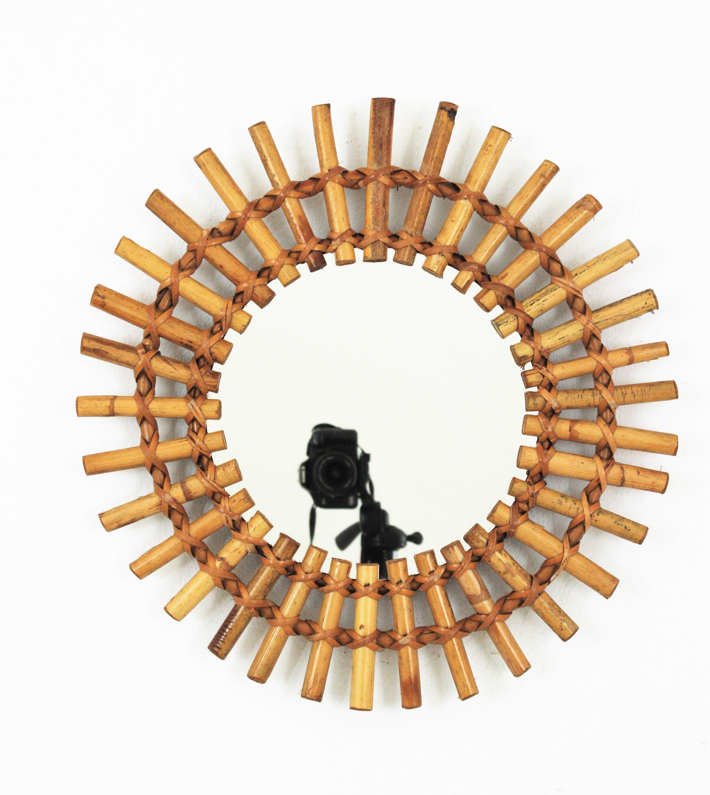A beautiful sunburst mirror handcrafted in rattan, and split bamboo. France, 1950s
Its design combines Midcentury and Tiki style accents.
This wall mirror will be a nice addition to a large sunburst mirror wall composition. 
Also lovely placed
