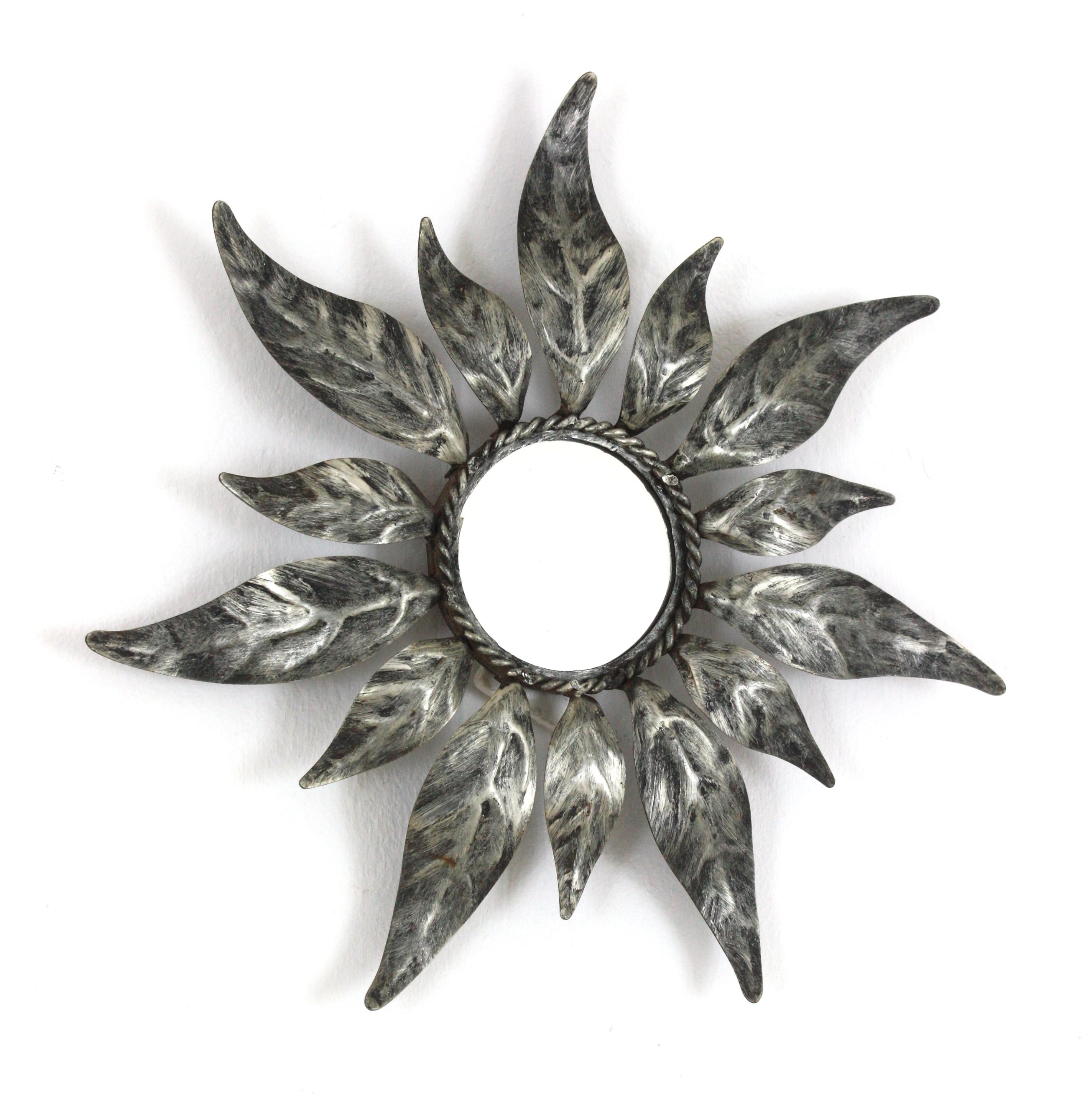 Spanish Mid-Century Modern Silvered Metal Leaf Design Mini Sized Sunburst Mirror. Spanien, 1950er Jahre.
Wunderschöner handgefertigter Spiegel aus vergoldetem Eisen mit Sonnenschliff und abwechselnden Blättern in zwei Größen und  Silber patiniertes