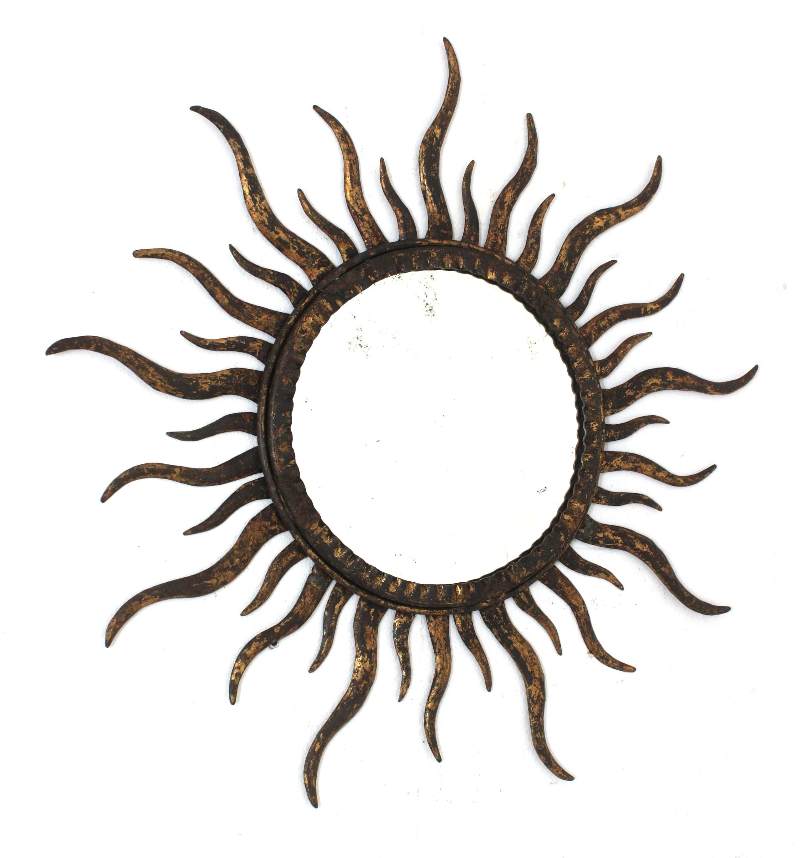 Sunburst mirror in the manner of Gilbert Poillerat, Parcel-Gilt Wrought Iron. France, 1940s.
This wall mirror has an eye-catching sunburst design with alternating rays in two sizes. Entirely made by hand in iron. Terrific aged patina and original