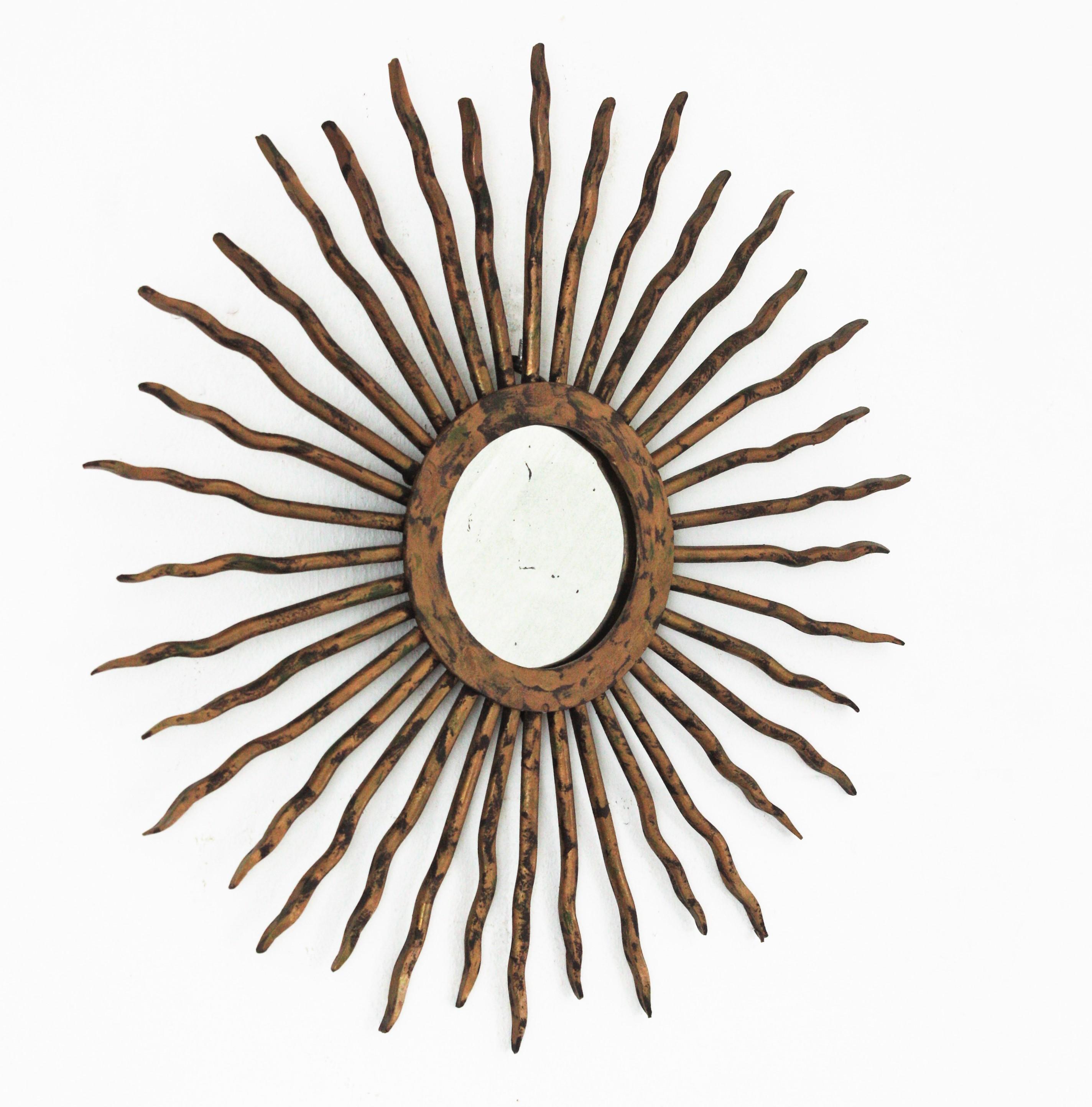 Sunburst mirror in hand forged iron and gilt patina. France, 1940s.
This sunburst mirror features a frame made of hand forged spikes attached to a central ring. Gilt patinated finish.
Terrific aged patina and eye-catching design.
This mirror will be