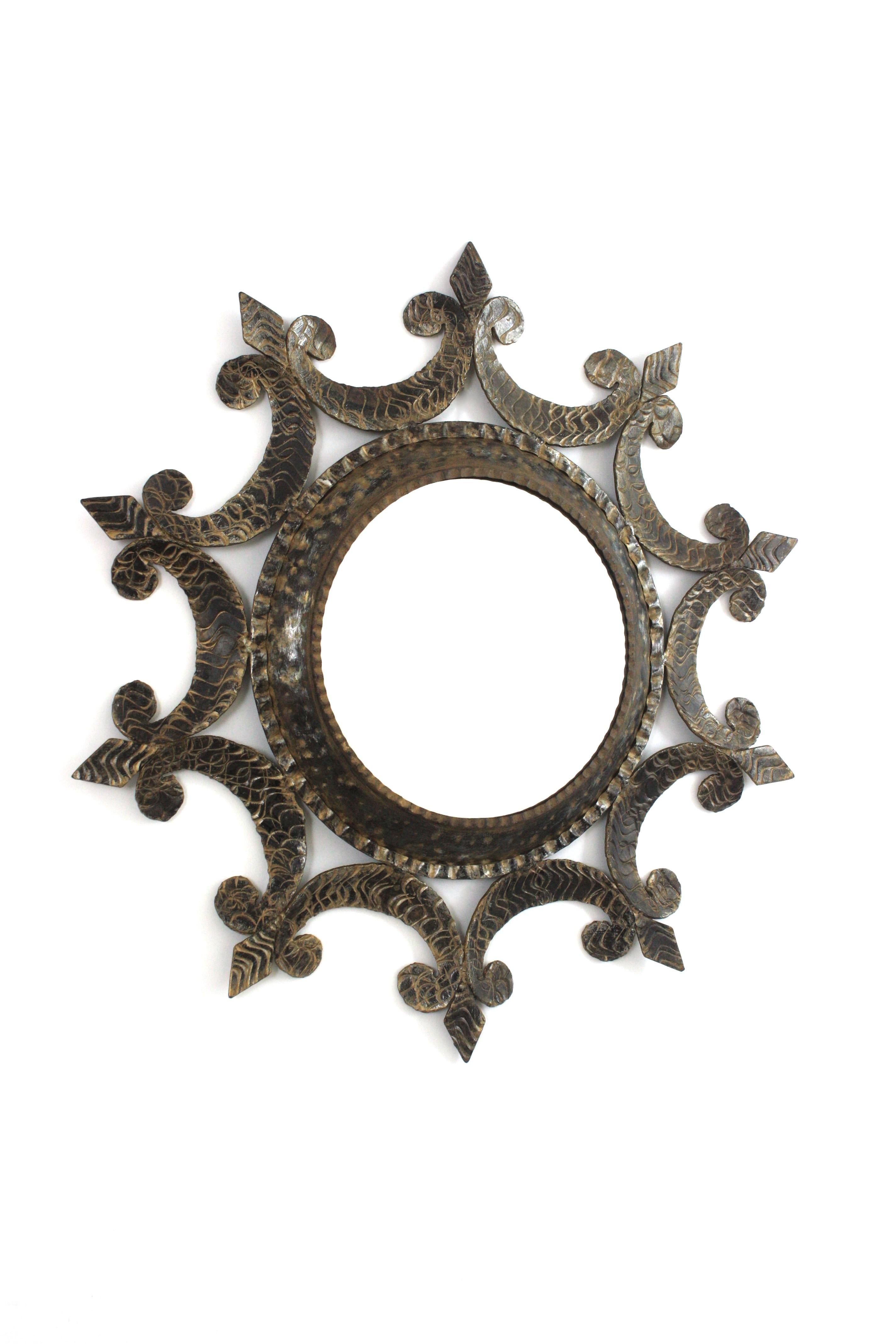 Wrought Iron Sunburst Mirror with Scroll Details and Brutalist Design, Spain, 1950-1960.
Eye-catching hand forged iron mirror with scroll decorations, fleur-de-lis accents and round shape.
This beautiful oval mirror is heavily decorated by