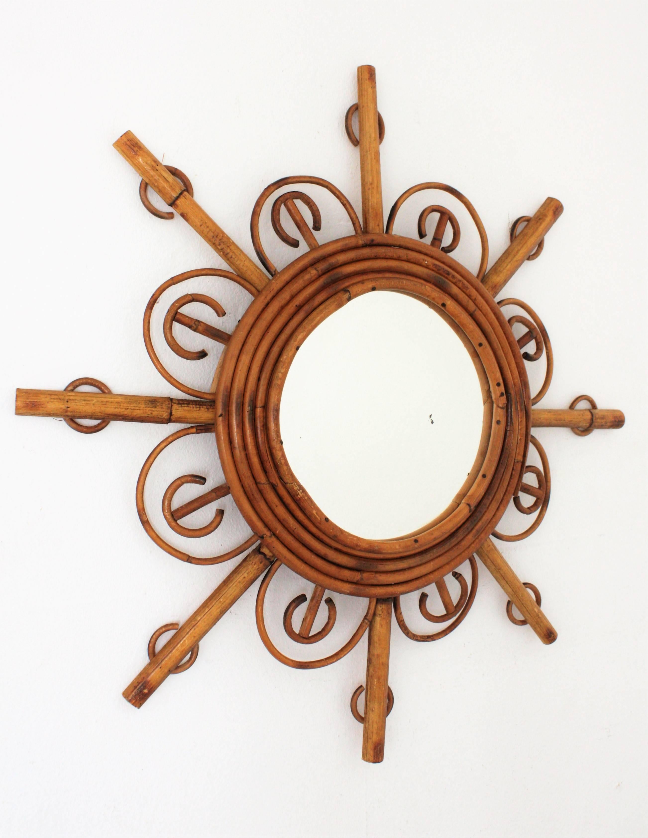 Beautiful French Riviera rattan and bamboo sunburst flower mirror. France, 1950s.
A circular glass framed by four bamboo cane laps and adorned by an alternating composition of petals and rays. This piece has all the taste of the French