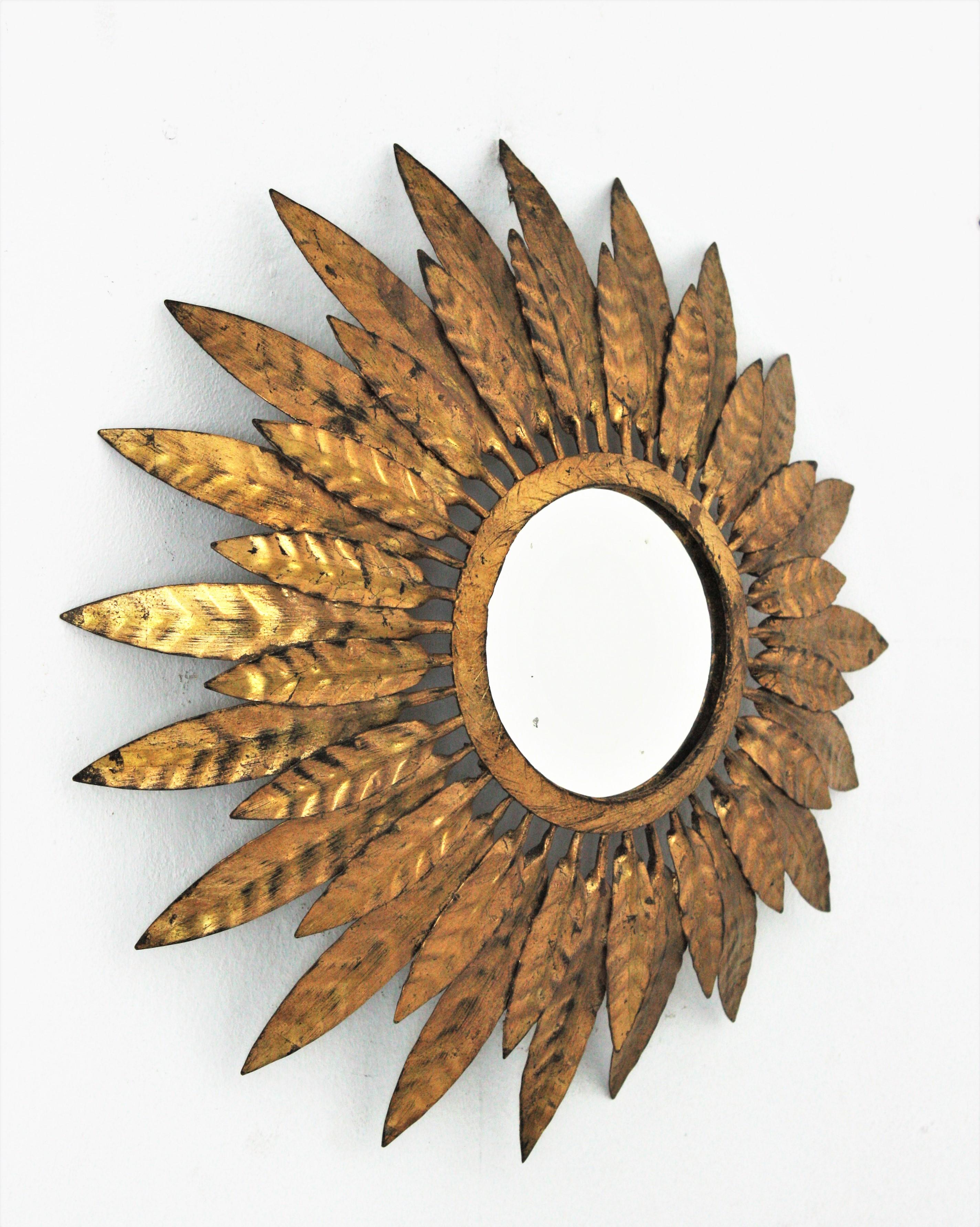 Sunburst mirror in gilt metal. Spain, 1950s.
Nice aged patina and beautiful design with double layered leafed frame.
Overall measures: 46 cm diameter ( 18,11 in diameter )
Glass diameter: 17 cm (6,69 in ).

     
