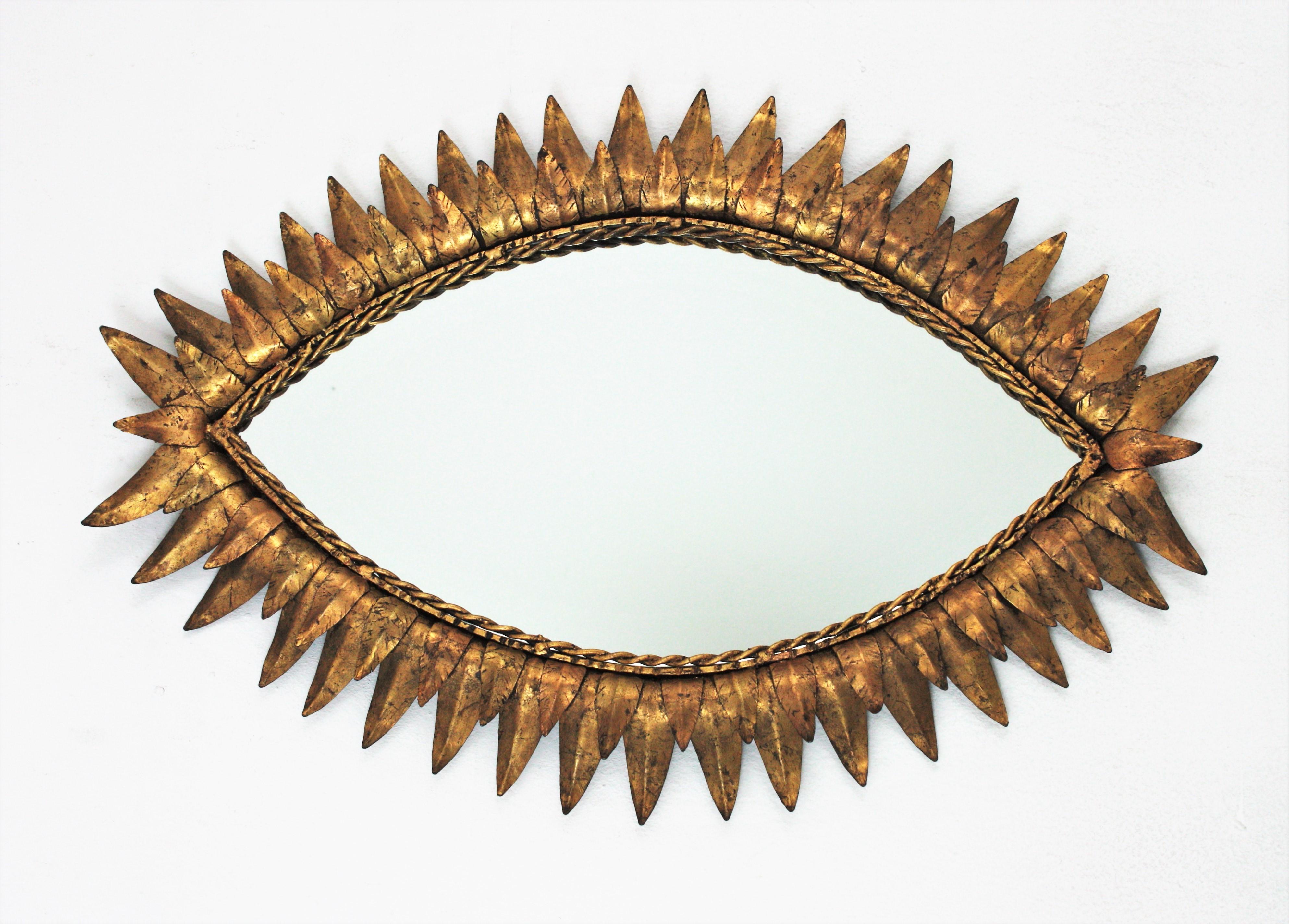 Mid-Century Modern eye shaped sunburst mirror, wrought iron, gold leaf, Spain, 1950s.
This pretty beautiful sunburst mirror features a double layered leafed frame in the shape of an eye. It has a nice color and patina and it shows its original gold