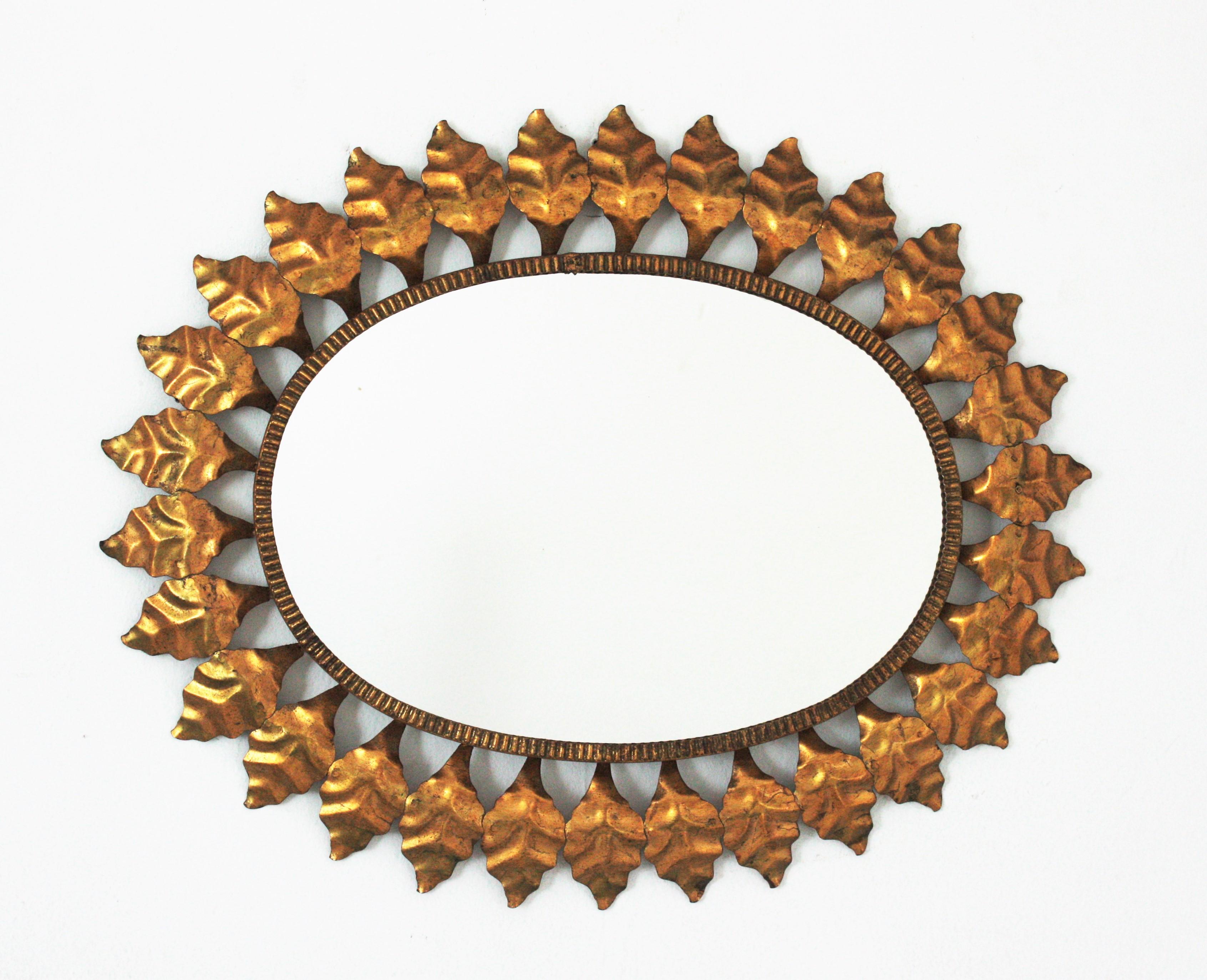 Mid-Century Modern wrought iron sunburst oval wall mirror with gold leaf finish, Spain, 1950s.
This highly decorative leafed sunburst gilt iron mirror has a nice color. It has terrific aged patina showing its original gold leaf gilding.
A great
