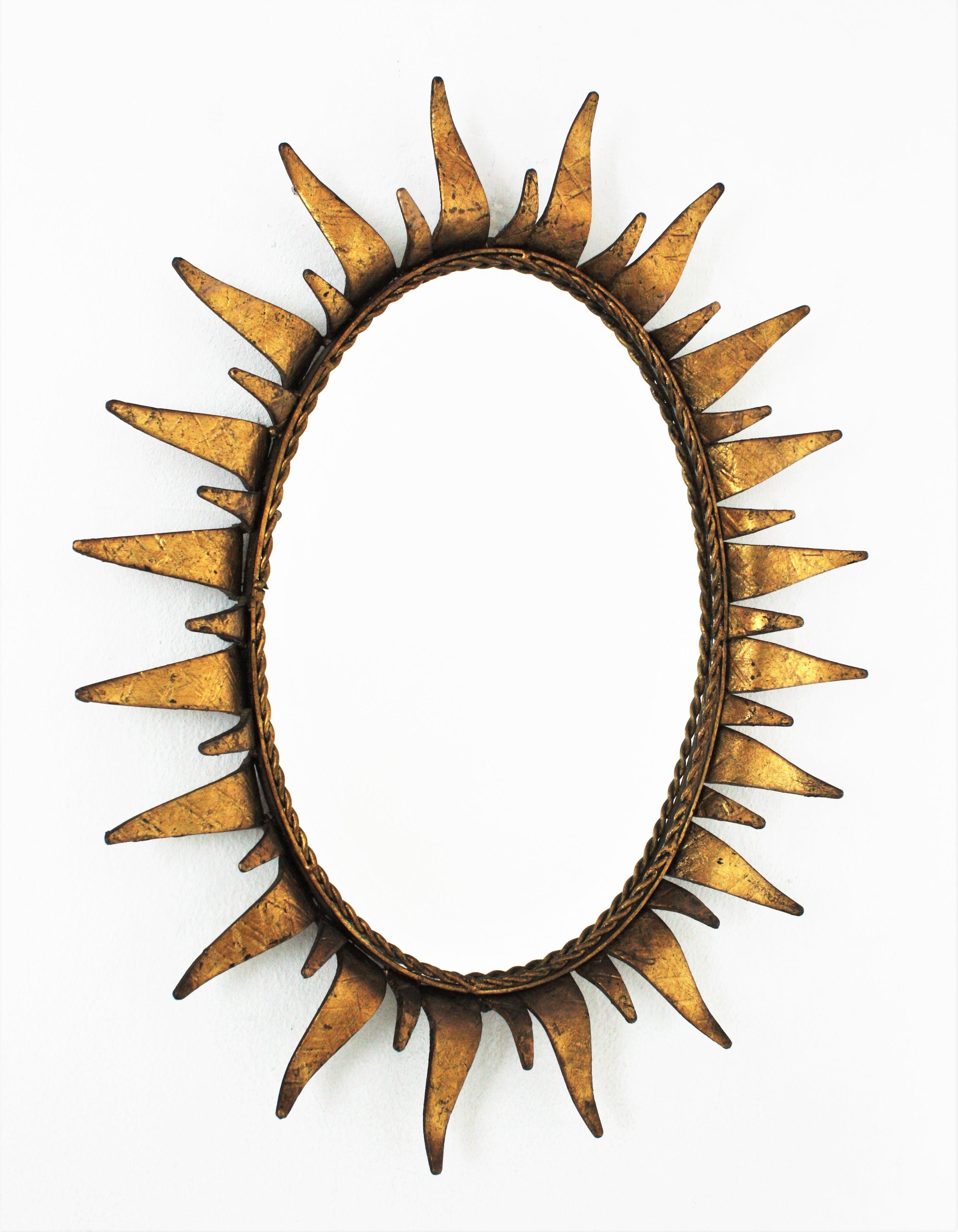 Mid-Century Modern wrought iron sunburst oval wall mirror with gold leaf finish, Spain, 1950s.
This highly decorative sunburst gilt iron mirror has a nice color. It has terrific aged patina showing its original gold leaf gilding.The rays are