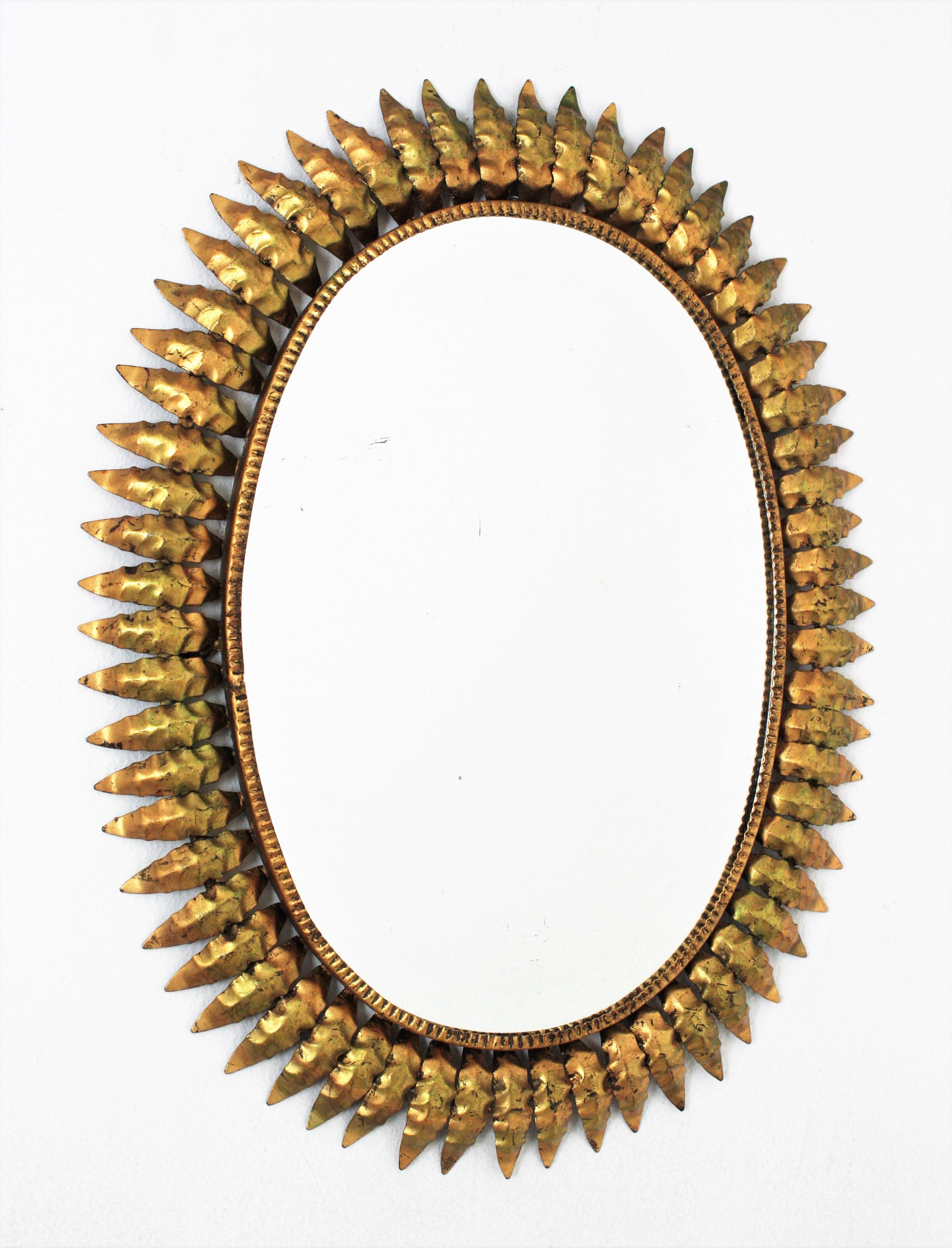 Spanishs sunburst mirror, Gold Leaf, Iron, 1950s
Mid-Century Modern hand-hammered iron sunburst oval wall mirror with gold leaf finish
This highly decorative leafed sunburst gilt iron mirror has a nice patina and gold leaf gilding and green