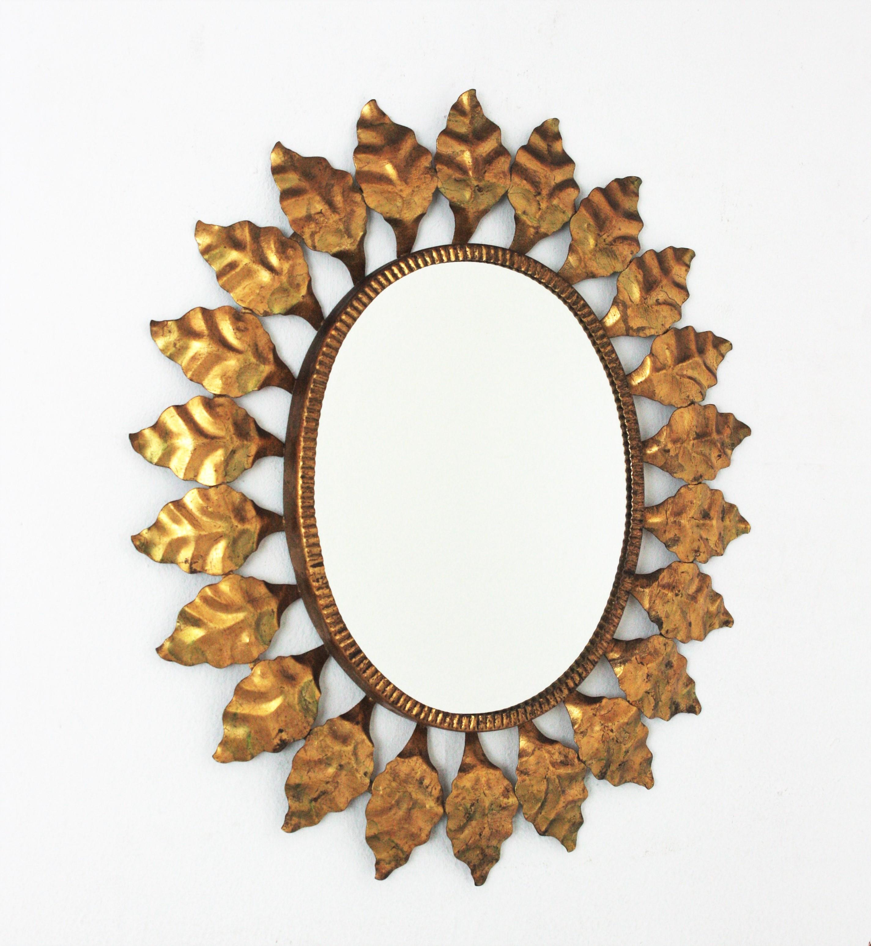 Small Mid-Century Modern wrought iron sunburst oval wall mirror with gold leaf finish, Spain, 1950s.
This highly decorative leafed sunburst gilt iron mirror has a nice color. It has terrific aged patina showing its original gold leaf gilding.
A