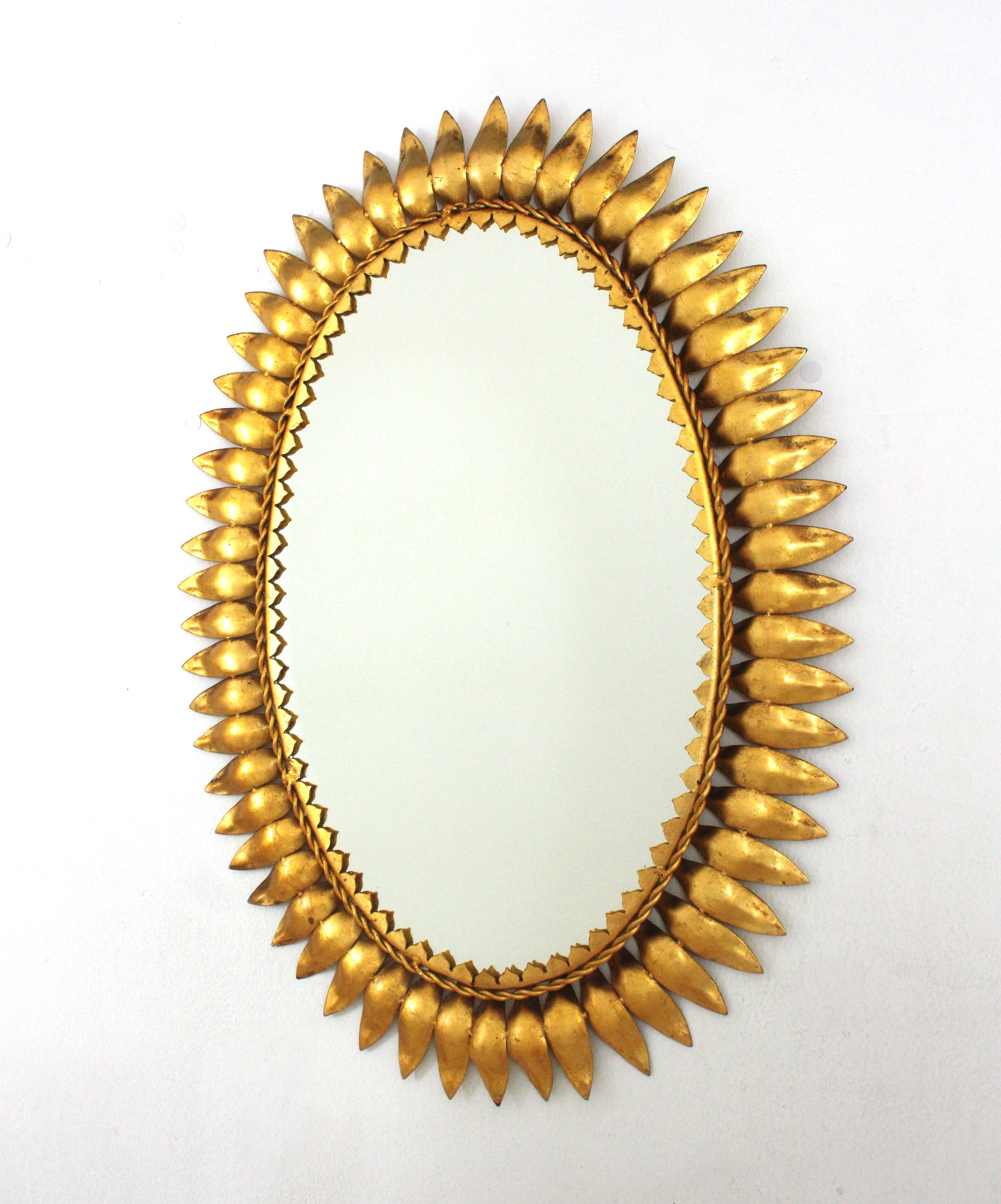 Gilt lron Sunburst Oval Wall Mirror
Mid-Century Modern iron sunburst oval wall mirror with leafed frame and gold leaf finish, Spain, 1950s.
This eye-catching sunburst mirror has a nice patina showing its original gold leaf gilding.
Placed over a