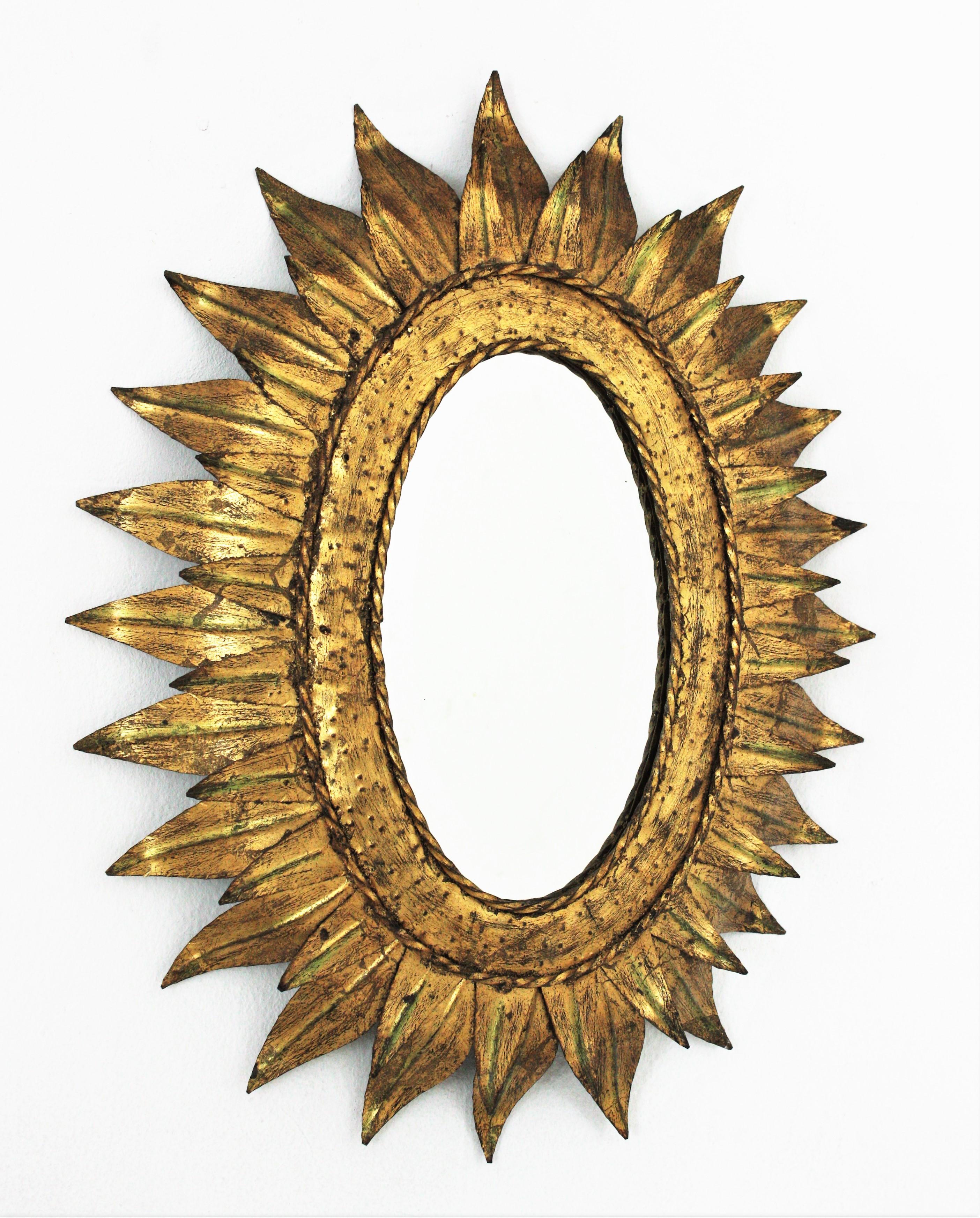 Sunburst oval mirror in gilt metal with double leafed frame, France, 1950s
This hand-hammered iron sunburst wall mirror features double leafed oval frame. It is heavily adorned by the hammer marks at the central part with twisting iron ropes