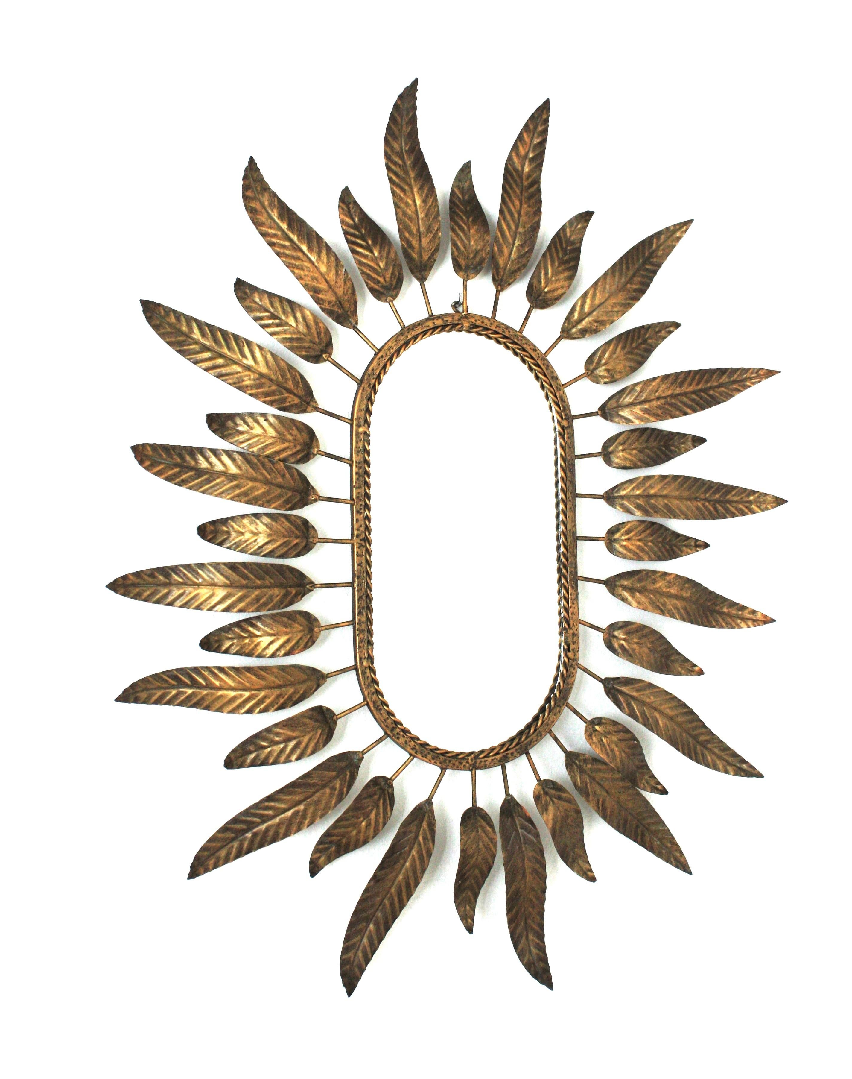 Spiegel mit Sonnenschliff aus vergoldetem Metall, umrahmt von Blättern. Spanien, 1950er-1960er Jahre.

Dieser stilvolle Spiegel kombiniert Midcentury- und Hollywood-Regency-Akzente: ein hochdekorativer ovaler Spiegel mit Sonnenschliff und