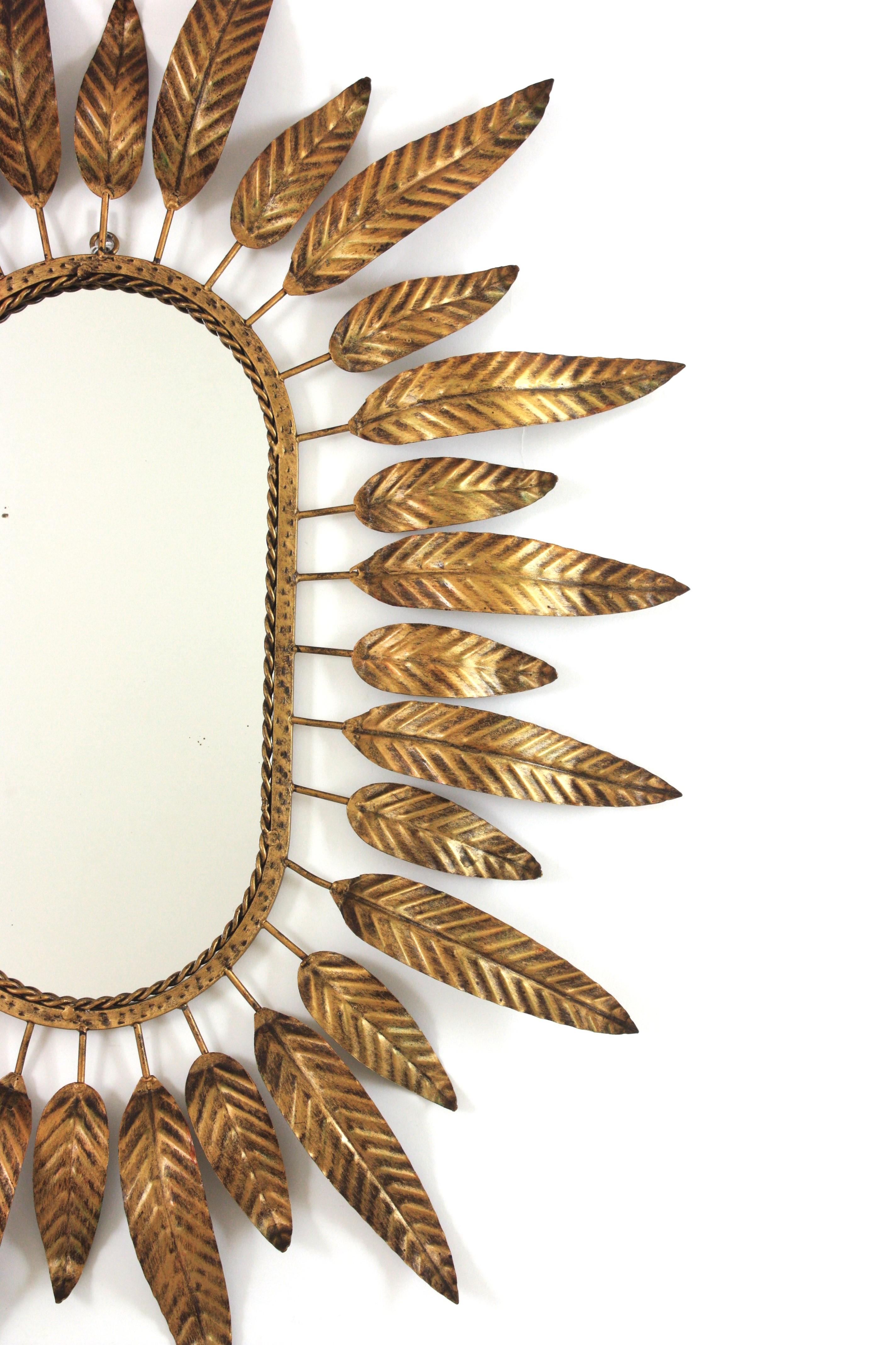 Metallo Specchio ovale Sunburst in metallo dorato con cornice fogliacea in vendita