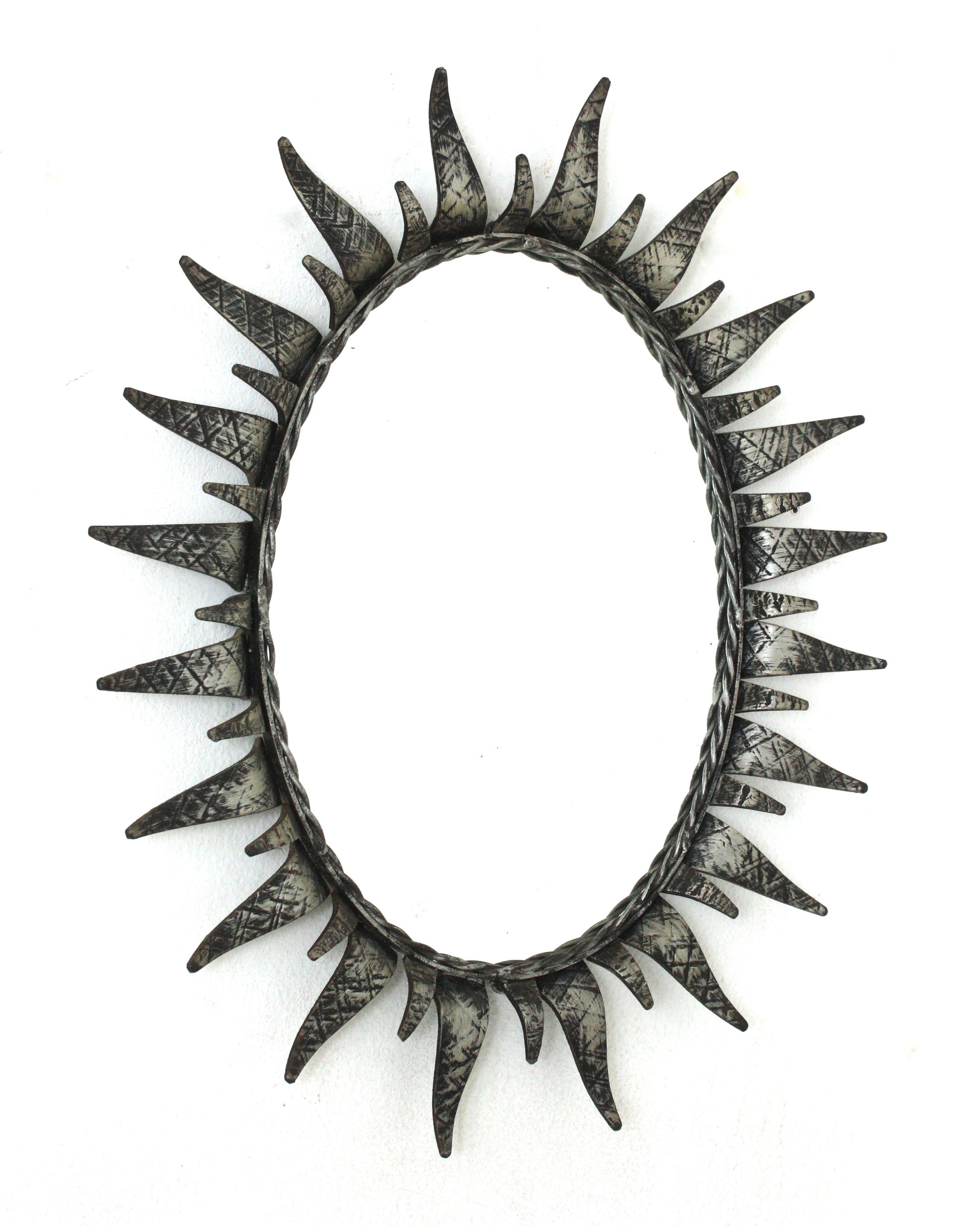 Mid-Century Modern wrought iron sunburst oval wall mirror with gilt silvered finish, Spain, 1950s.
This highly decorative sunburst iron mirror has a nice silver patinated color. It has terrific aged patina showing its original silvered finish. The