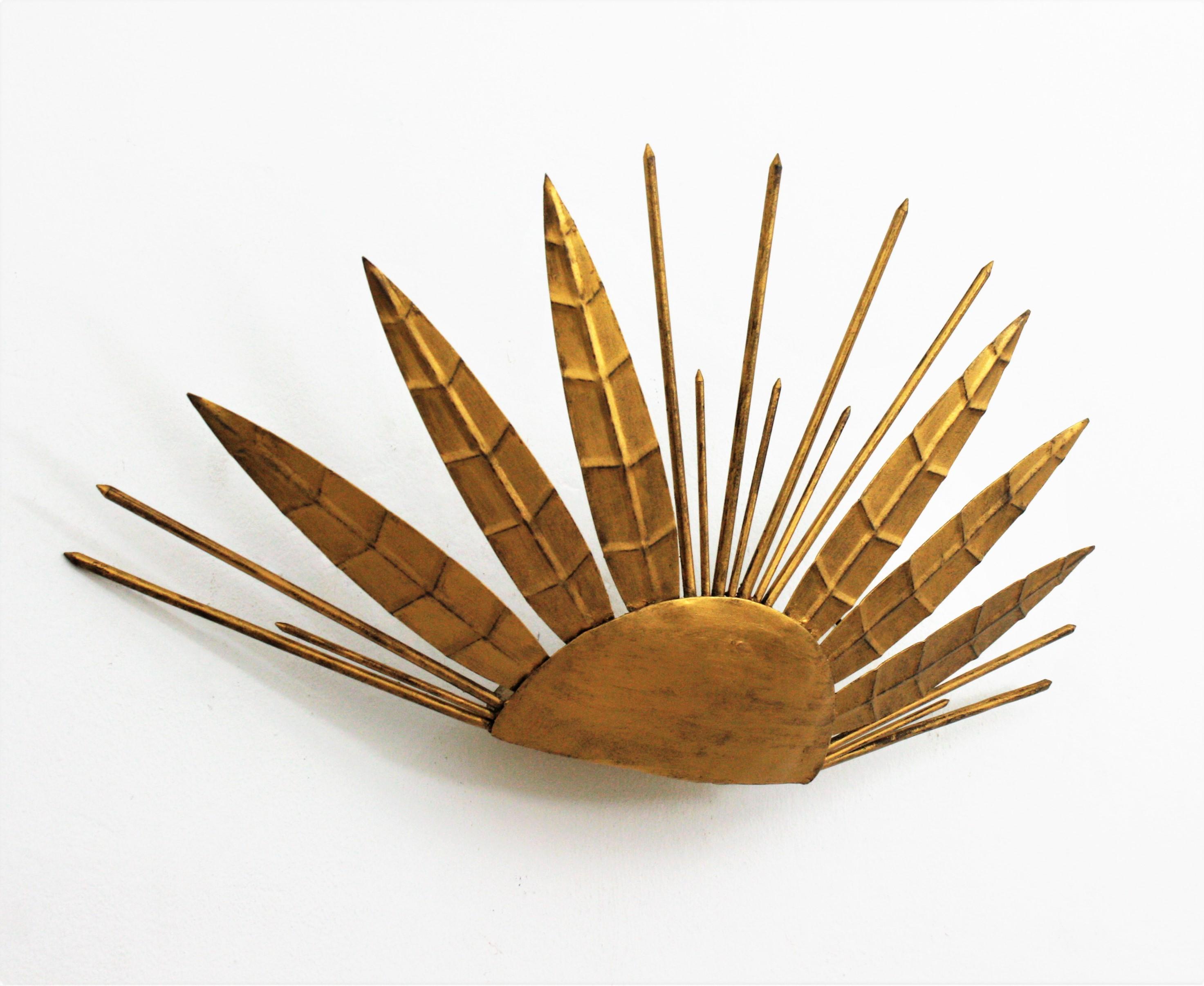 Unusual half sunburst shape wall sconce with leaf and nail accents from the late Art Deco period, France, 1940s-1950s.
This raising sun sunburst light is highly decorative due to its design with alternating iron leaves with pointed spikes.
It has