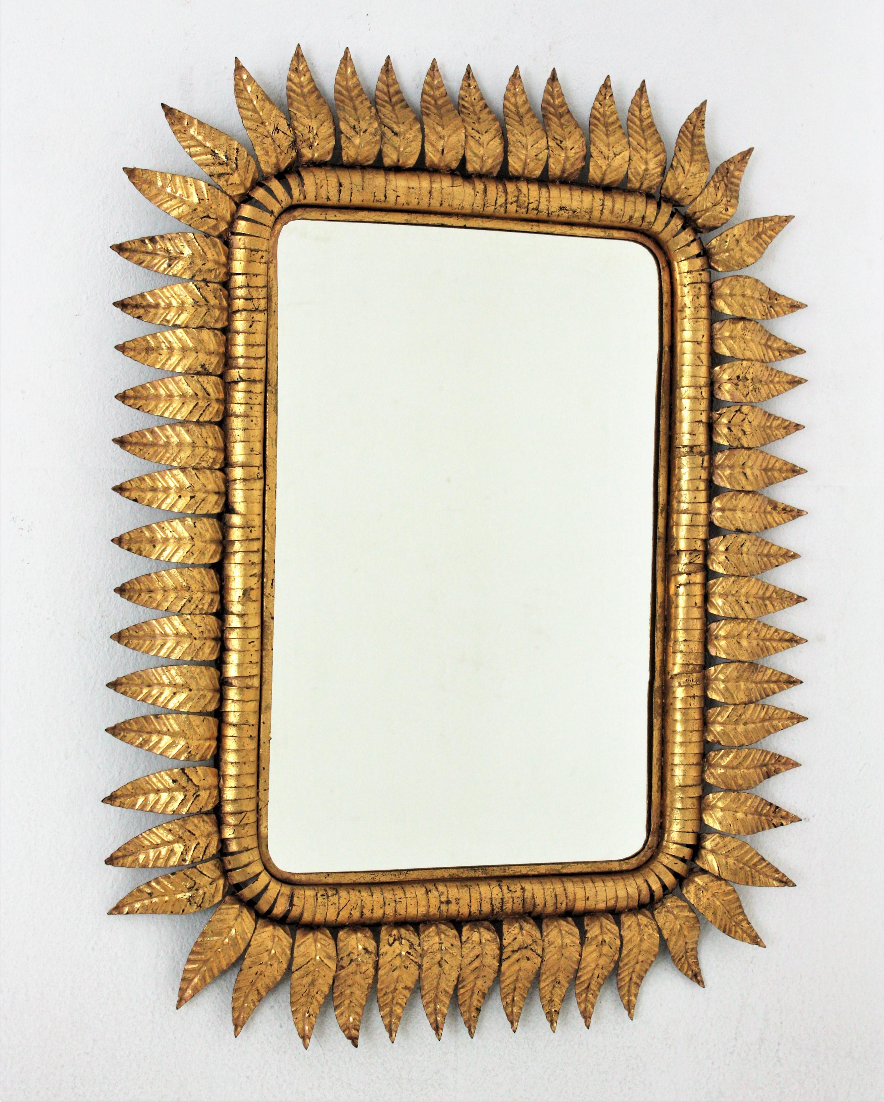 Hand-hammered iron sunburst rectangular wall mirror with gold leaf finish, Spain, 1950s.
Highly decorative rectangular leaf framed sunburst mirrors with gold leaf gilding.
Entirely made by hand. Very detailed work surrounding the mirror glass. It