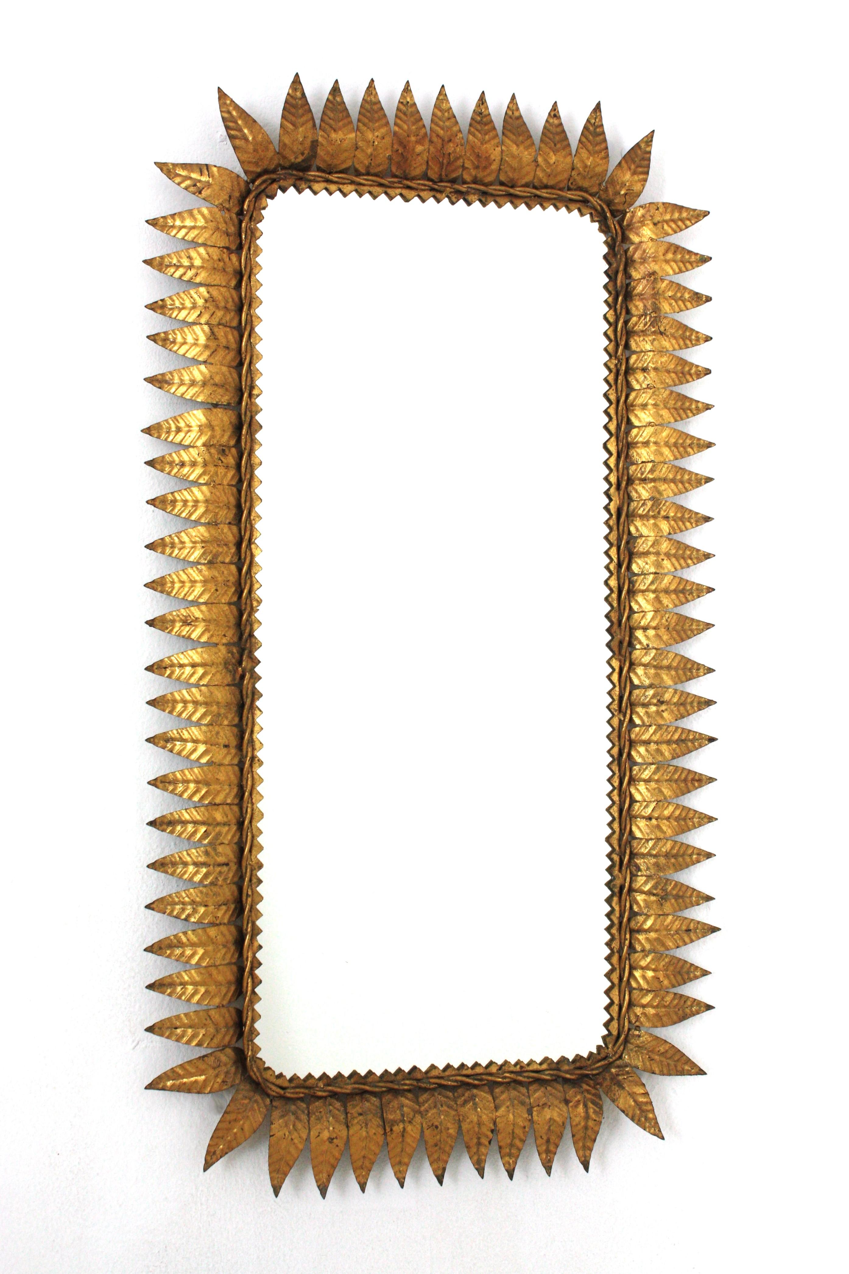 Wrought Gilt iron sunburst rectangular wall mirror with gold leaf finish, France, 1940s.
Highly decorative rectangular leaf framed sunburst mirror with gold leaf gilding.
Entirely made by hand. Twisted iron rope and eye-catching jagged edge