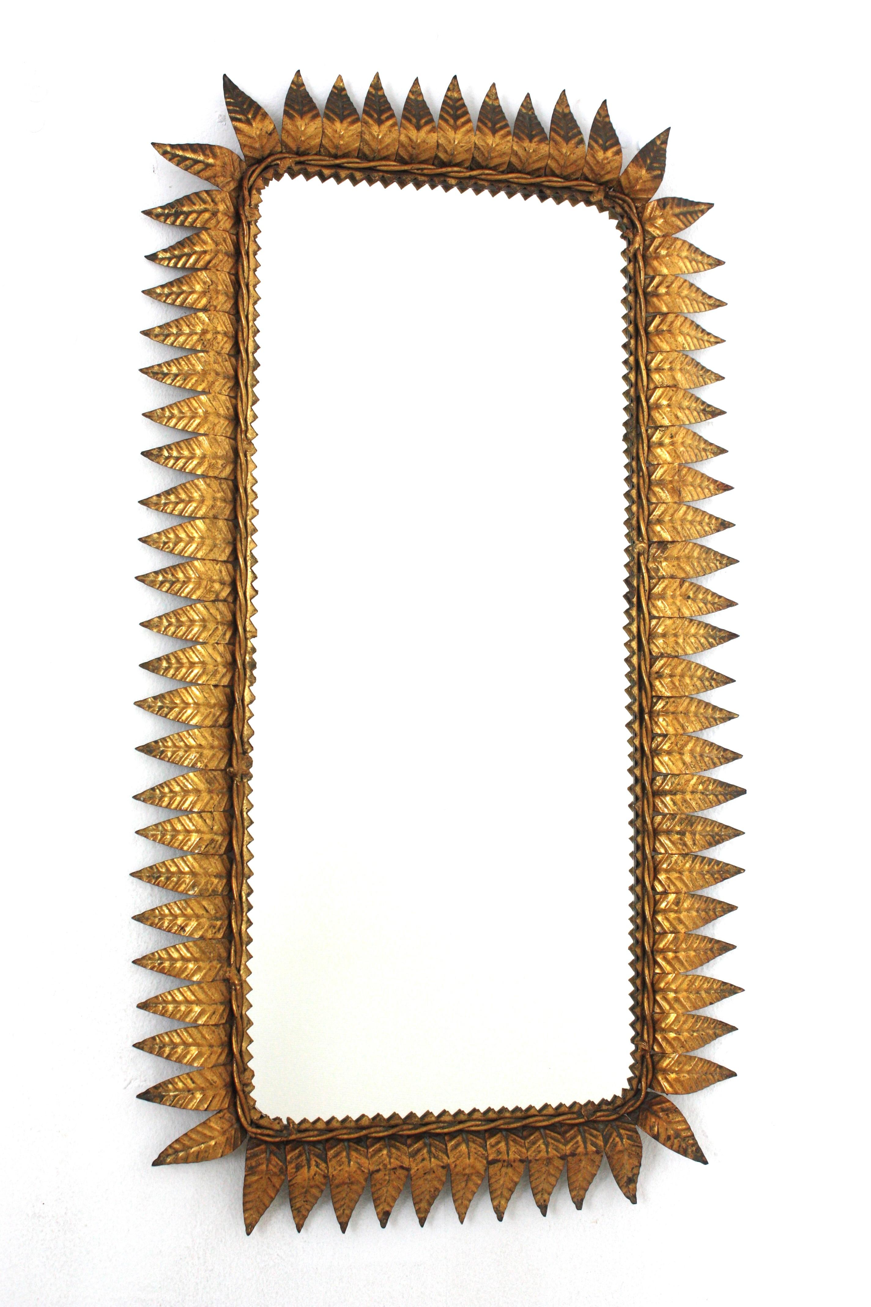 Wrought Gilt iron sunburst rectangular wall mirror with gold leaf finish, France, 1940s.
Highly decorative rectangular leaf framed sunburst mirror with gold leaf gilding.
Entirely made by hand. Twisted iron rope and eye-catching jagged edge