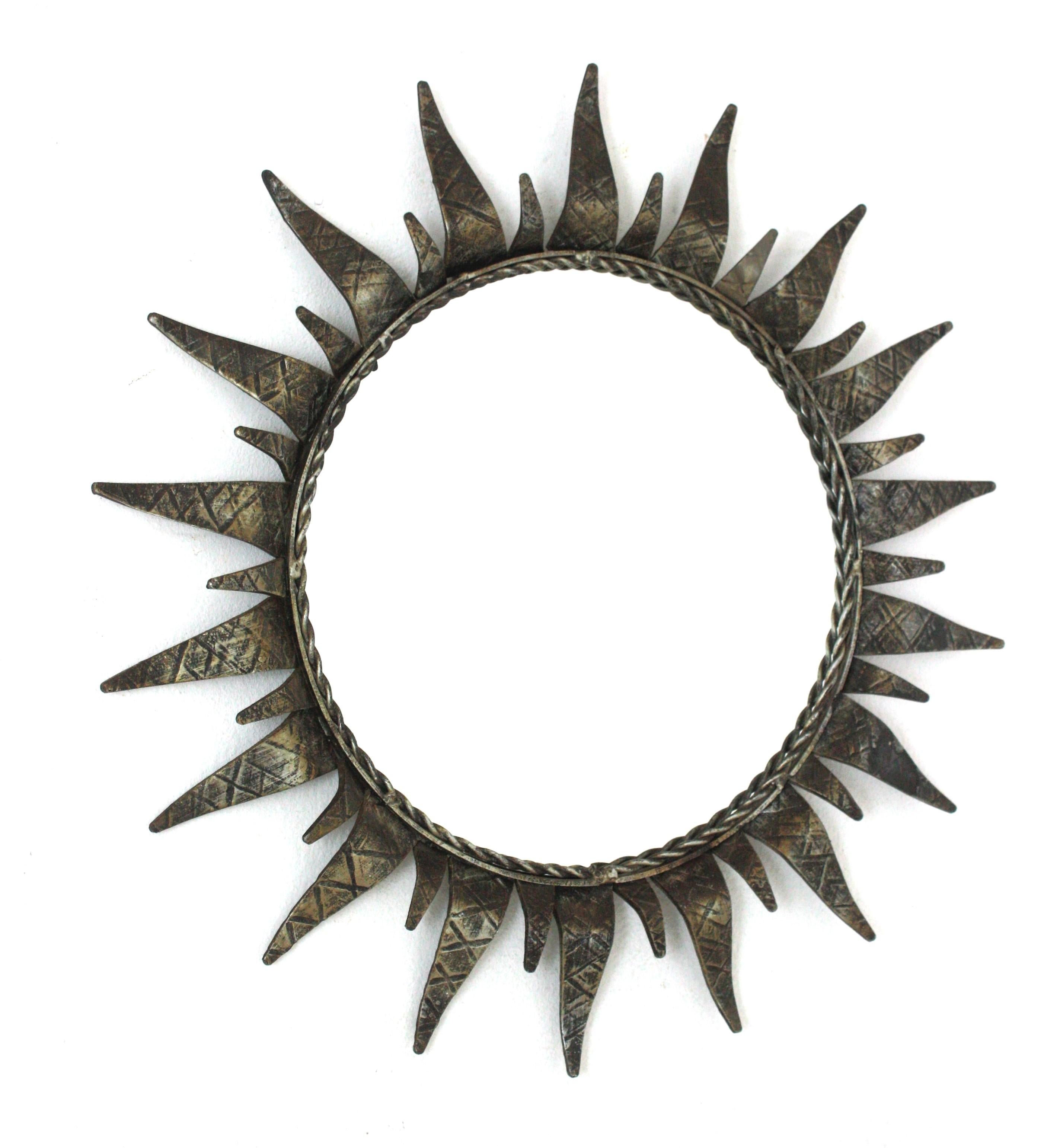 Round Sunburst Mirror in Silver Gilt Wrought Iron
Mid-Century Modern wrought iron sunburst round wall mirror with silvered gilt finish, Spain, 1950s.
This highly decorative sunburst gilt iron mirror has a nice silvered color and a terrific aged