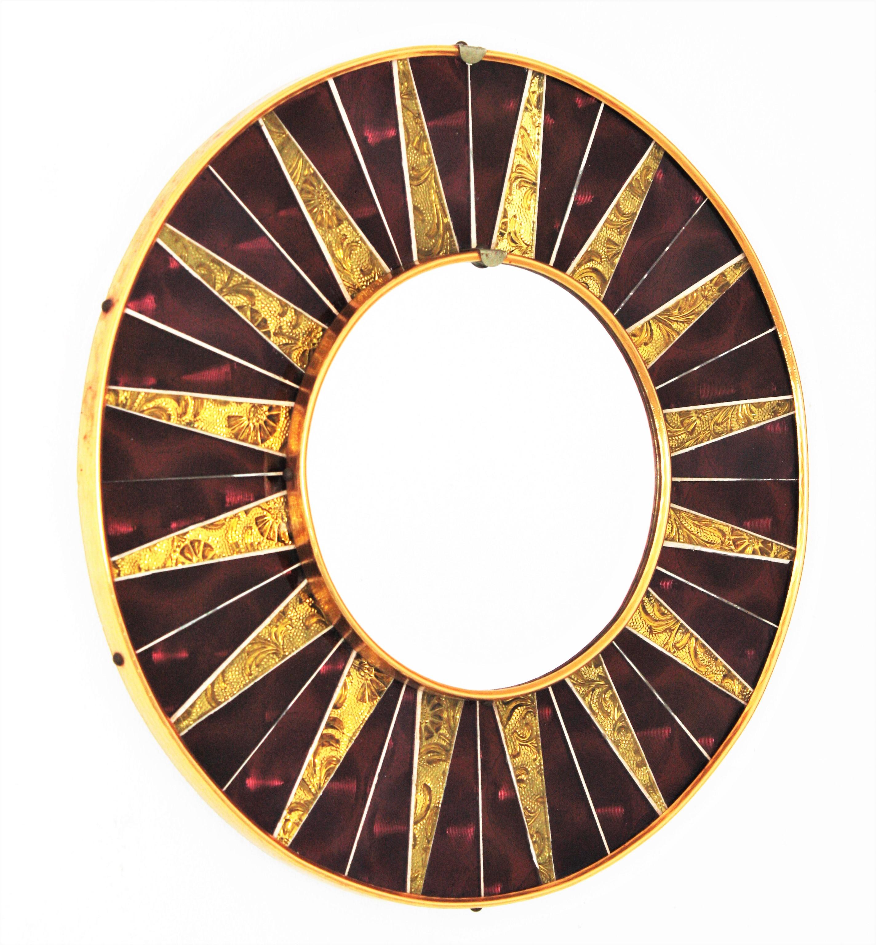 Ein stilvoller runder Spiegel der Jahrhundertmitte mit granat- und goldfarbenem Glasmosaikrahmen, Spanien, ca. 1960er Jahre.
Der Rahmen besteht aus einem Hintergrund aus burgunder- bzw. granatfarbenen Glasstücken und goldenen, verspiegelten