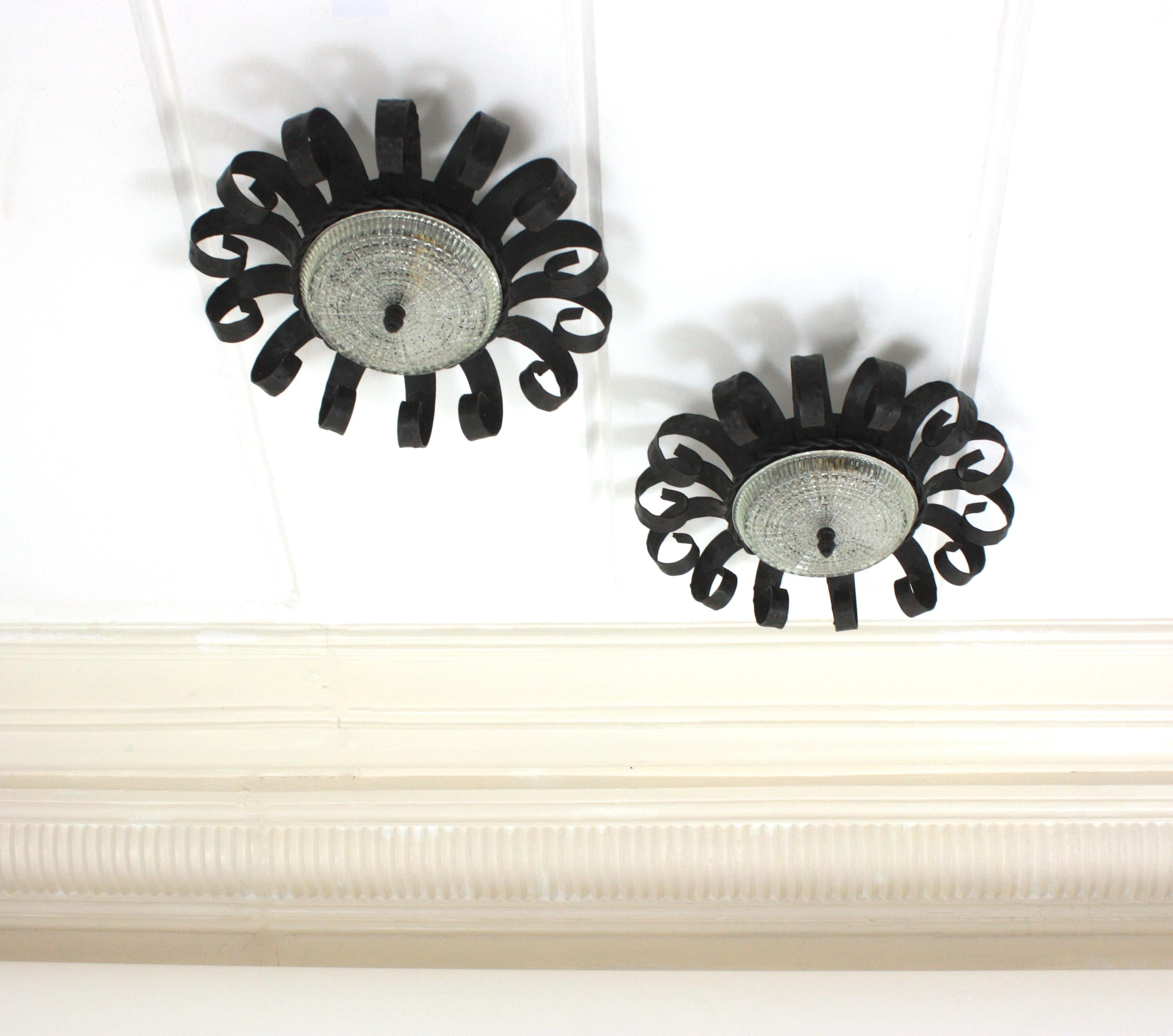 Paire d'objets Brutalist forgés à la main  Luminaires en fer avec abat-jour en verre pressé, Espagne, années 1950
Cette paire de luminaires en forme de couronne de soleil, fabriqués à la main, se caractérise par des cadres en fer forgé à volutes et